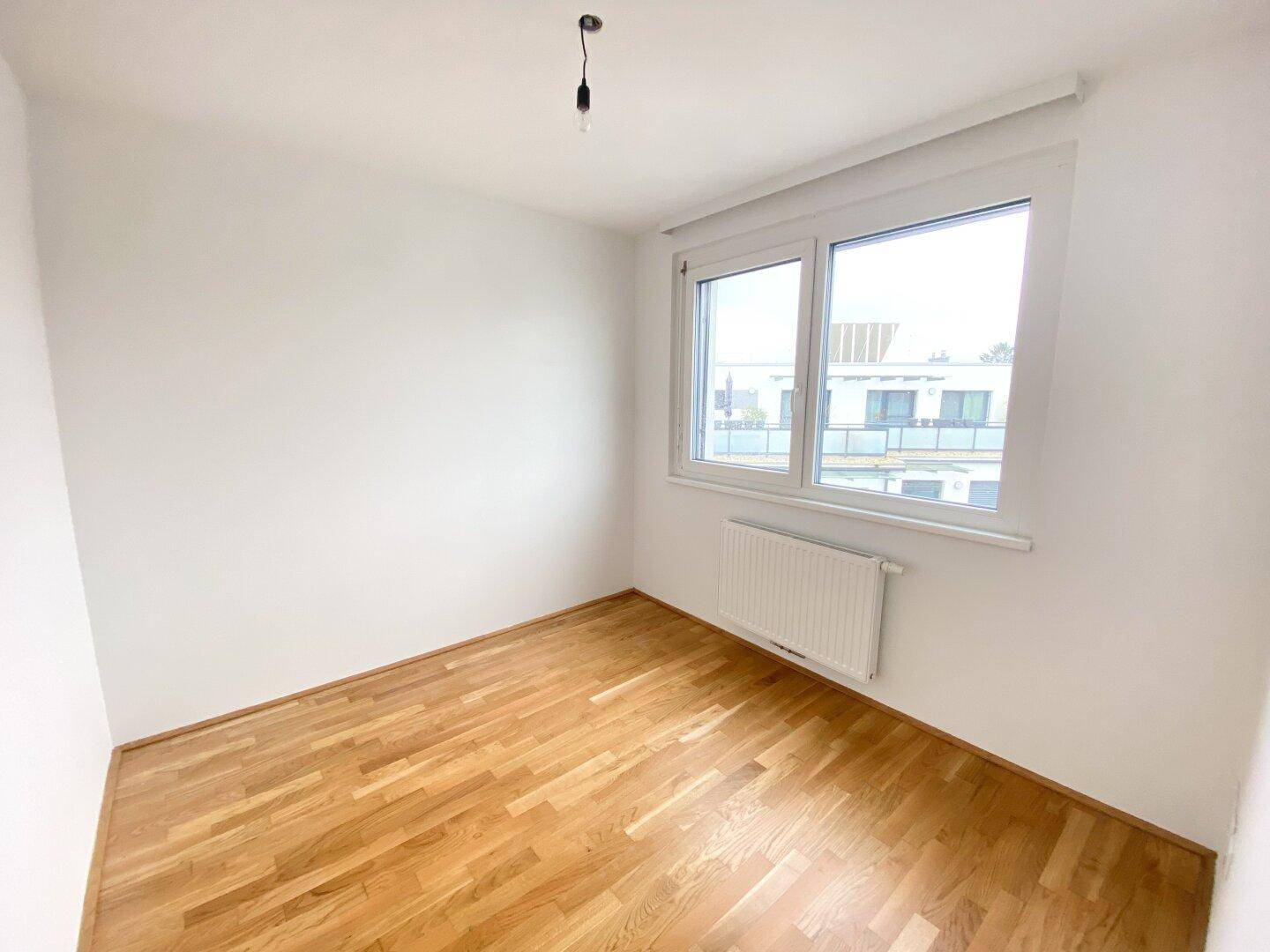 Gemütliches Schlafzimmer mit Parkettboden, großen Fenstern und Blick auf die Umgebung.