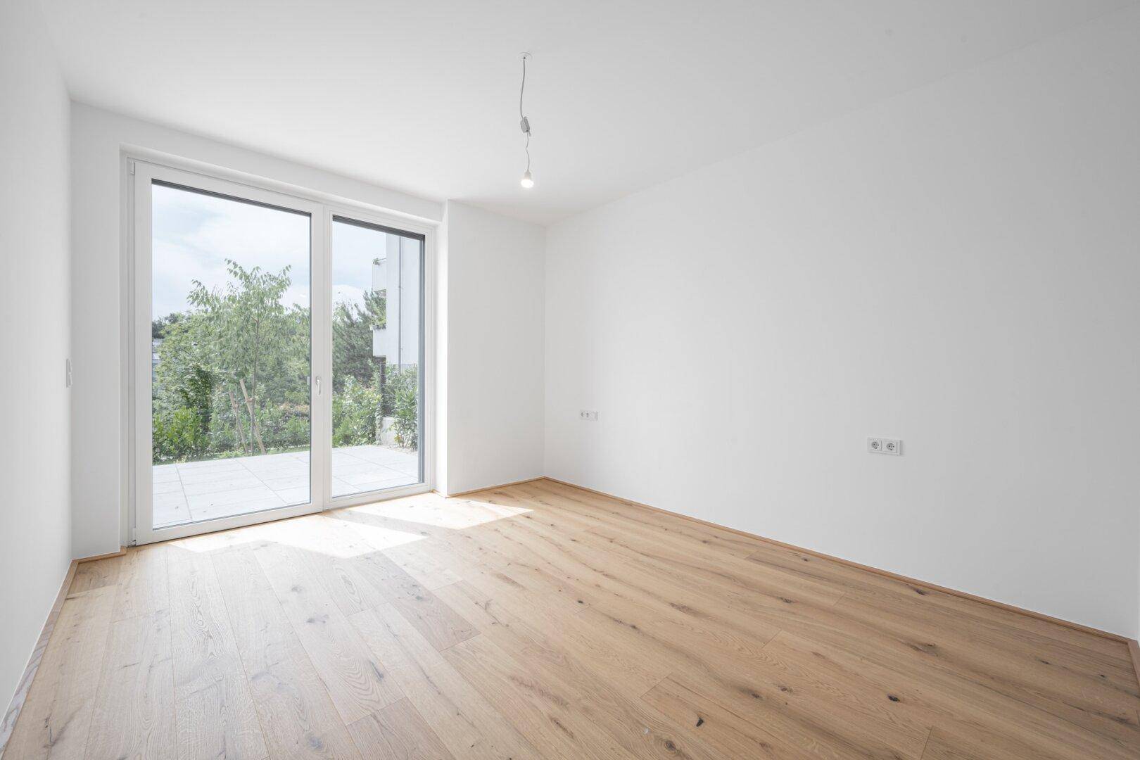 Geräumiger, heller Raum mit Holzboden und breiter Fensterfront für viel Tageslicht.