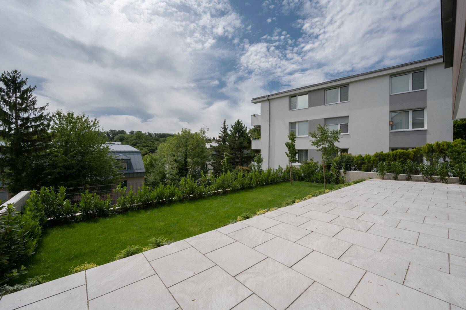 Weitläufige Terrasse mit gepflegtem Rasen und Hecke, ideal für Entspannung im Freien.