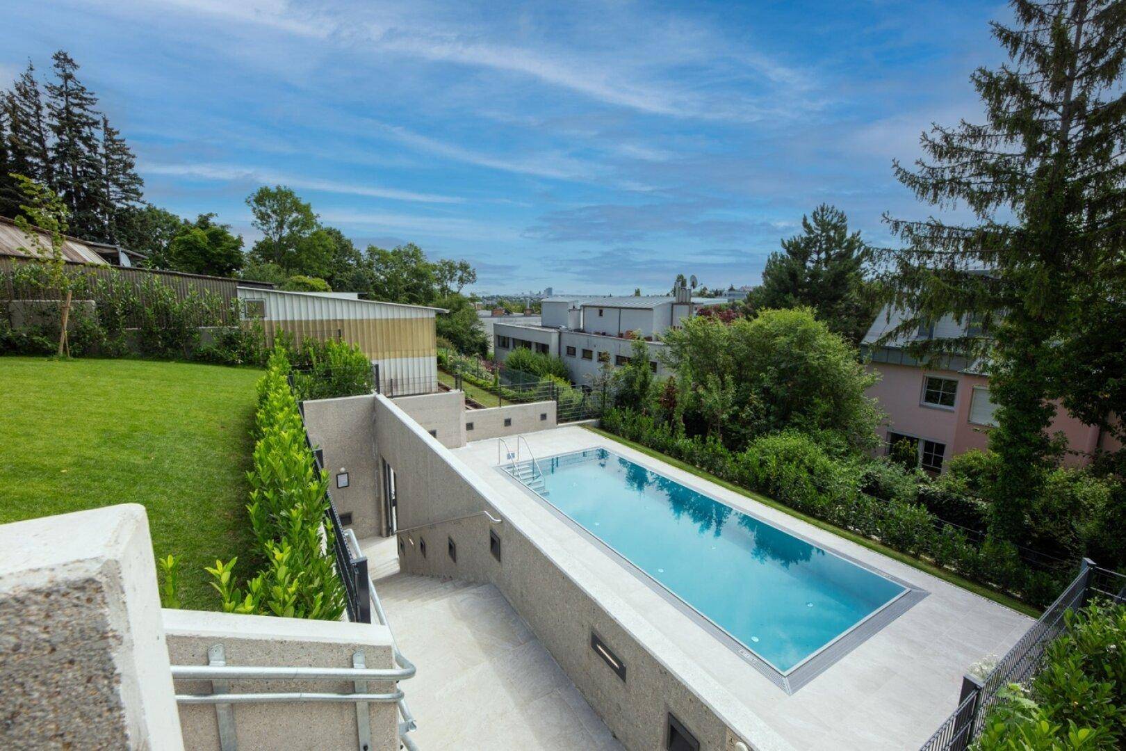 Weitläufiger Außenbereich mit großem Pool, Rasenfläche und Blick ins Grüne.