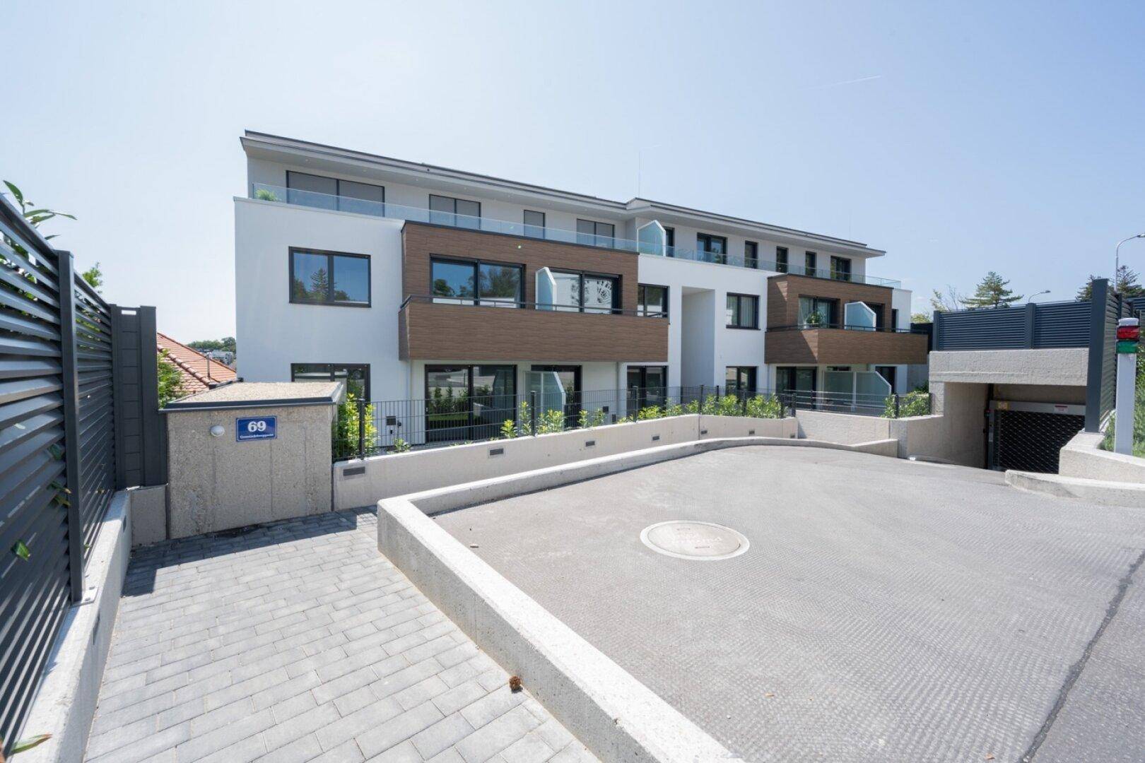 Moderne Wohnanlage mit ansprechender Fassade und Zufahrt zur Tiefgarage.