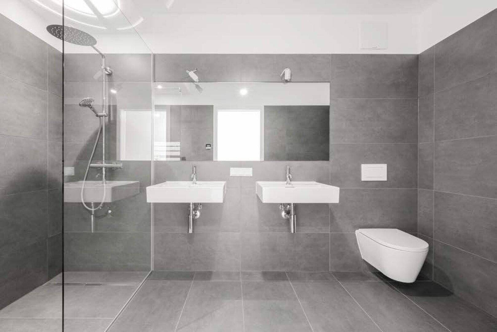 Modernes Badezimmer mit grauen Fliesen, Doppelwaschbecken und ebenerdiger Dusche.