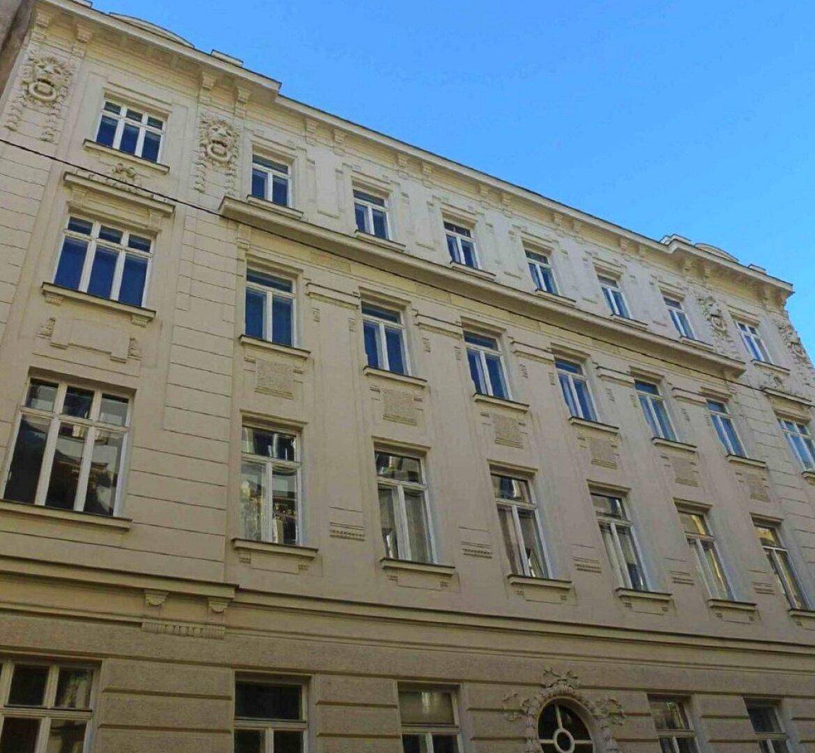 Klassische Fassade eines Altbaus mit vielen Fenstern und dekorativen architektonischen Details.