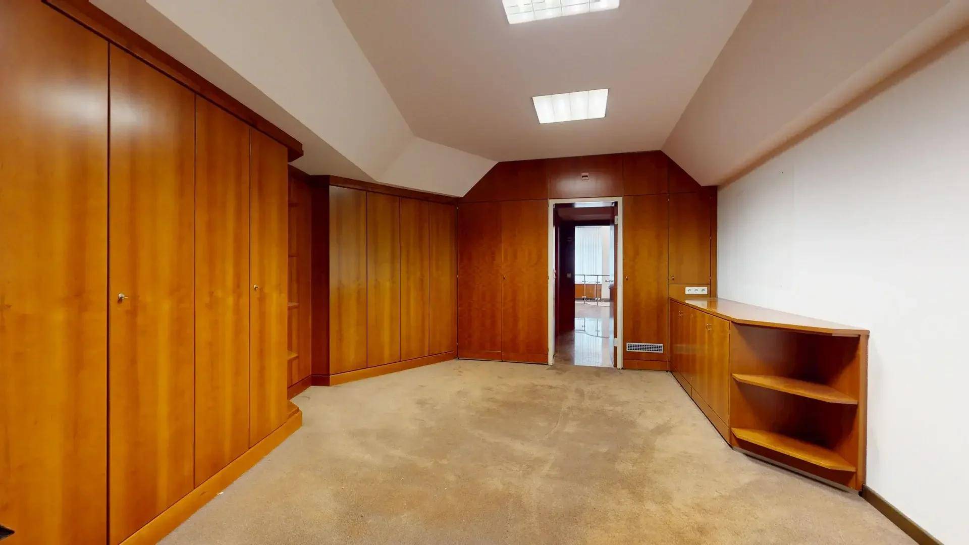 Privates Büro oder Besprechungszimmer mit Holzschränken, Teppichboden und einer abgehängten Decke.