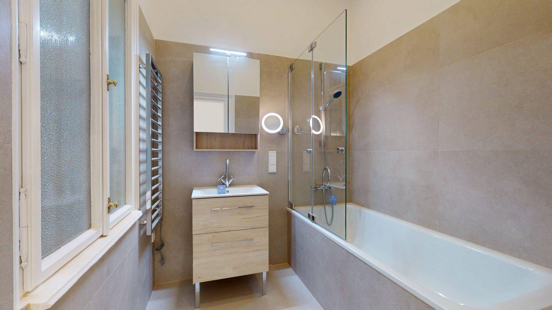Modernes Badezimmer mit Badewanne, Duschwand, Waschbecken und beheiztem Handtuchhalter.