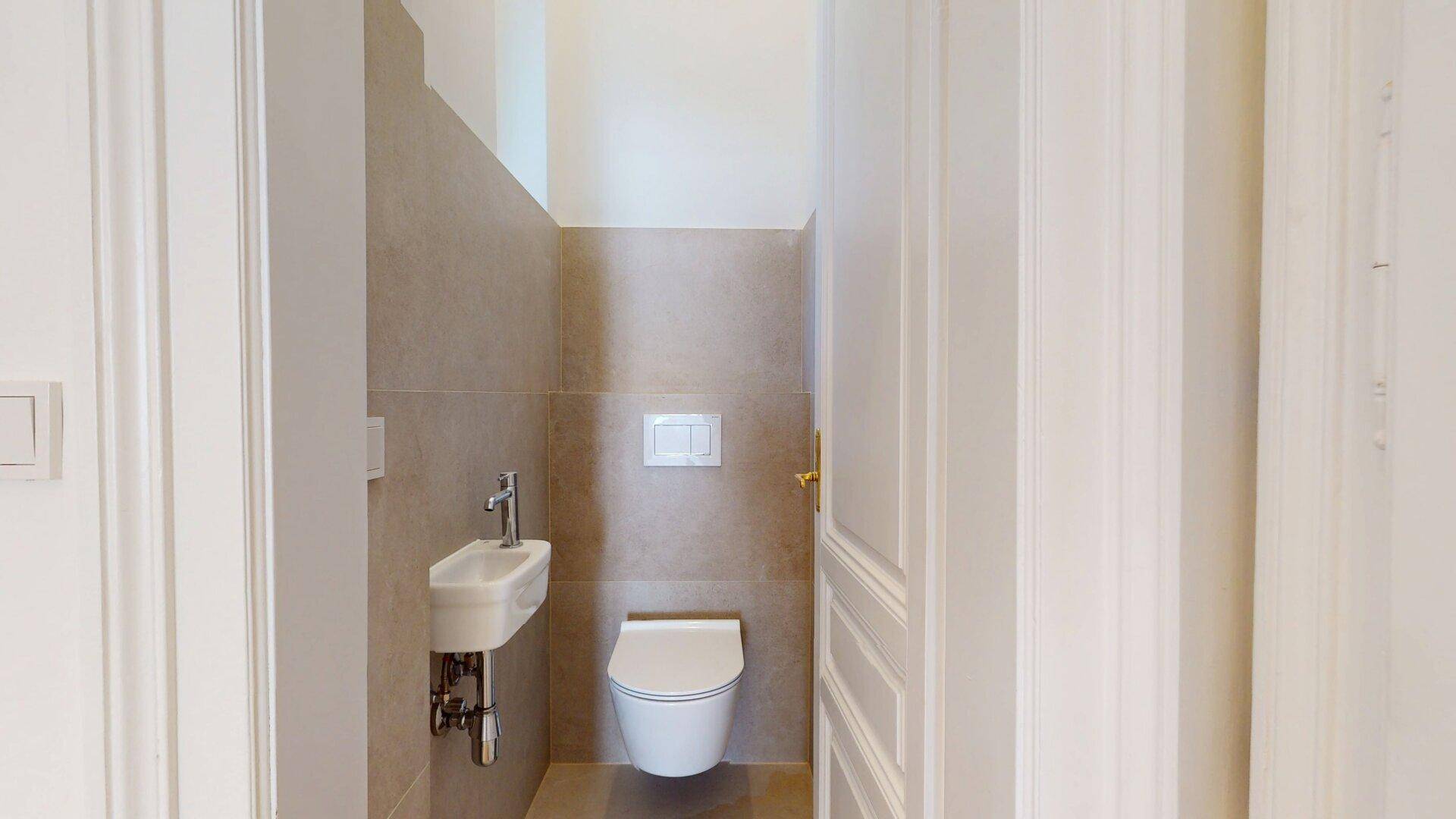 Kleines, modernes Gäste-WC mit Wand-WC und Handwaschbecken, in neutralen Farbtönen gehalten.