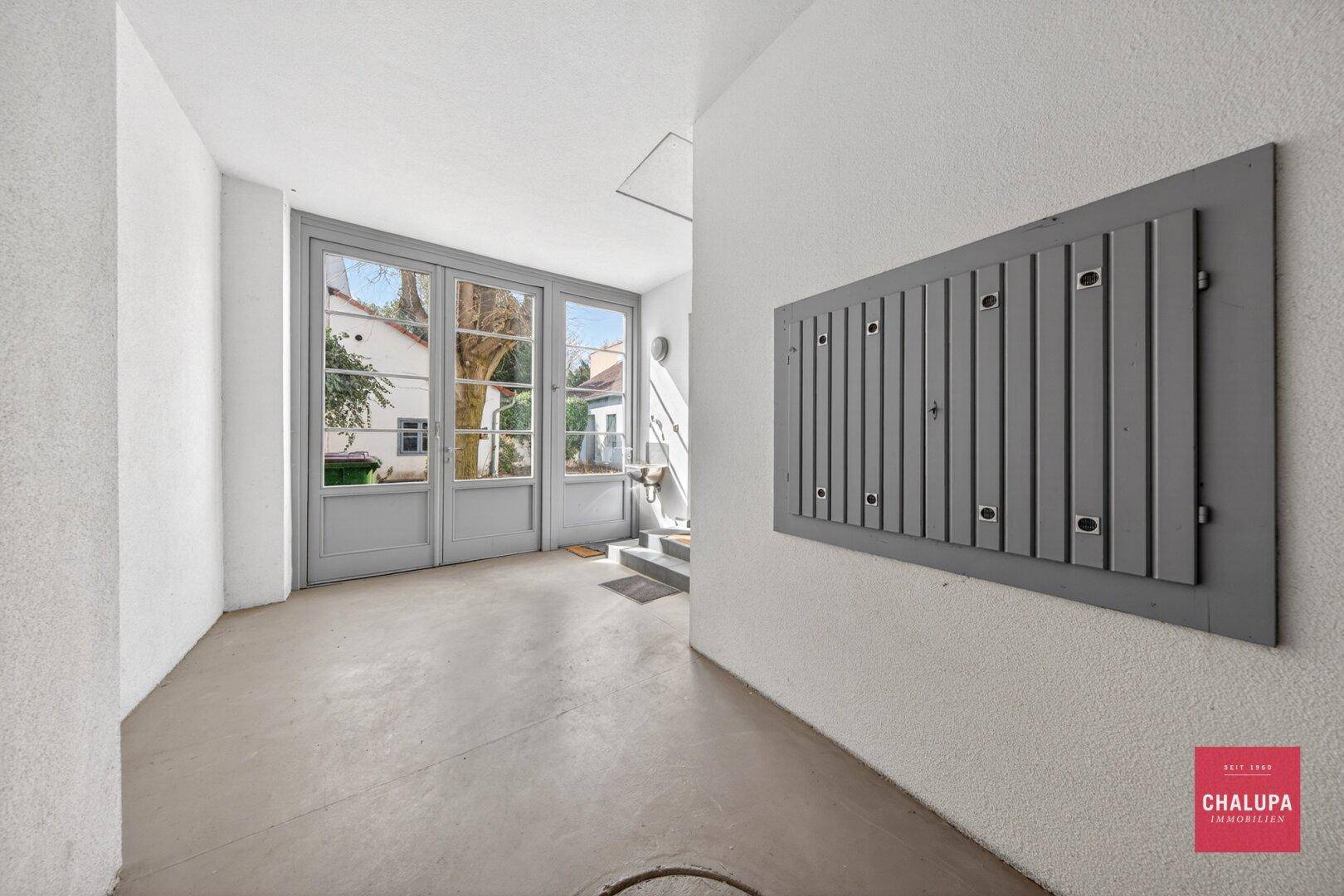 Heller Eingangsbereich mit großen Glastüren, die zum Außenbereich führen.