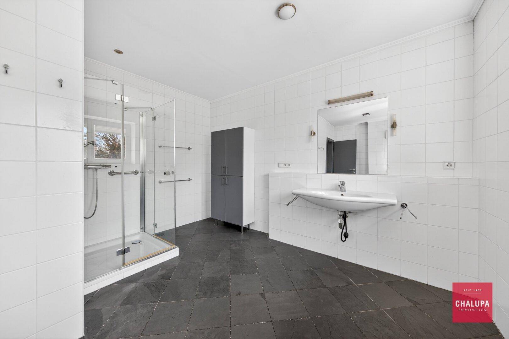 Modernes Badezimmer mit weißen Fliesen, Duschkabine und Einzelwaschbecken.