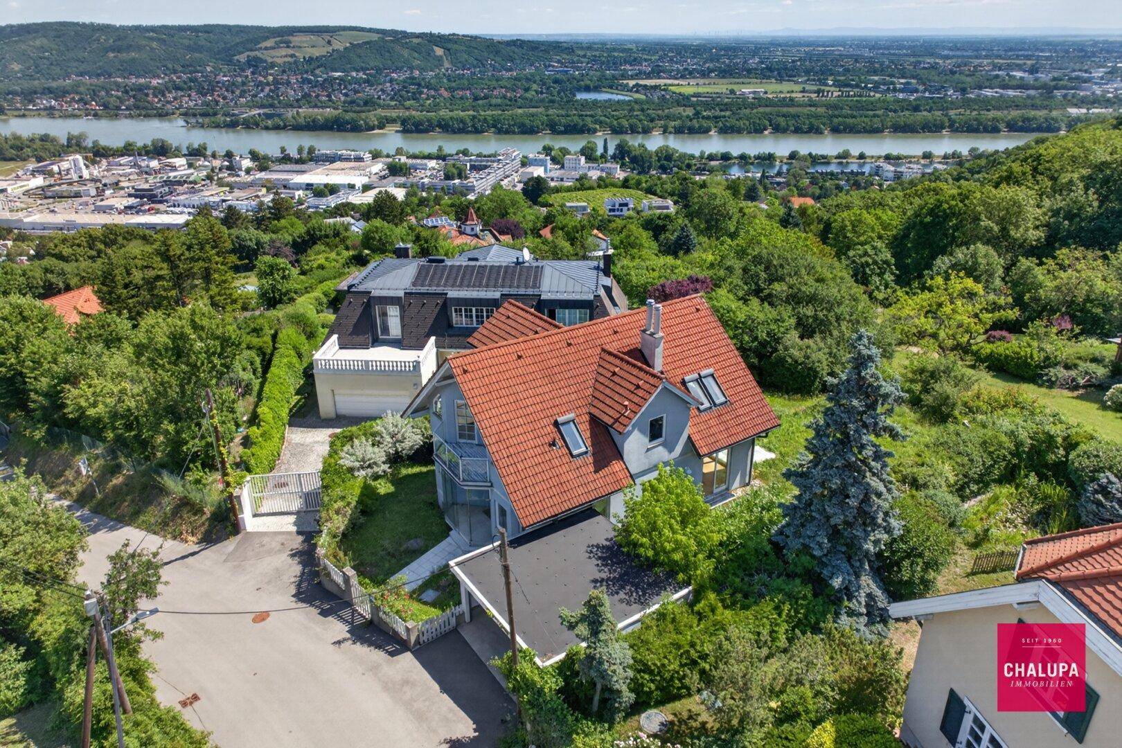 Luftaufnahme des Hauses mit umliegender grüner Landschaft und Fluss im Hintergrund.