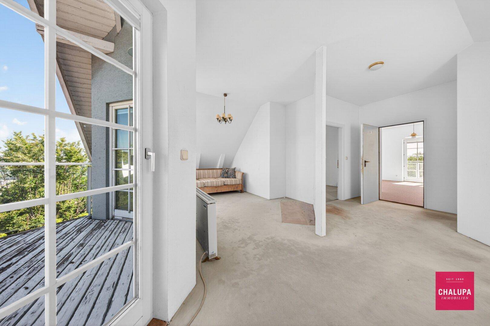Offener Dachgeschossbereich mit Teppichboden und Zugang zu einem Außenbalkon.