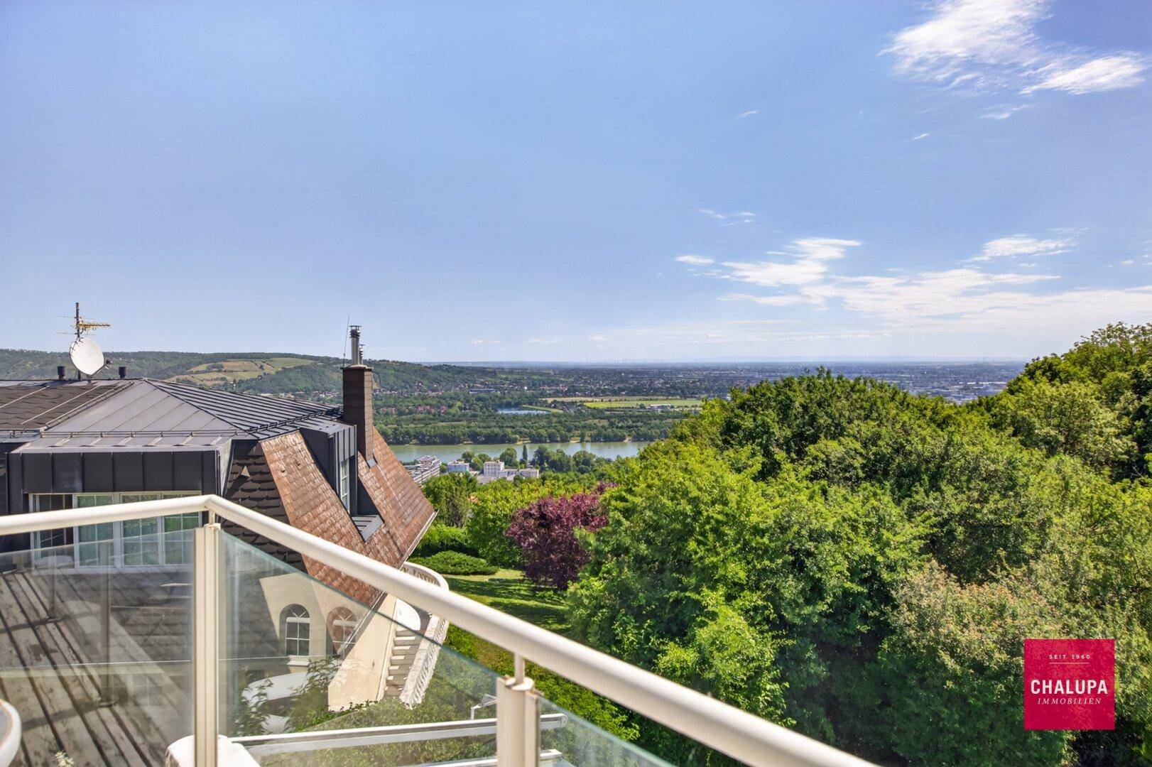 Balkon mit Holzboden und Glasgeländer bietet weiten Blick über die Landschaft.