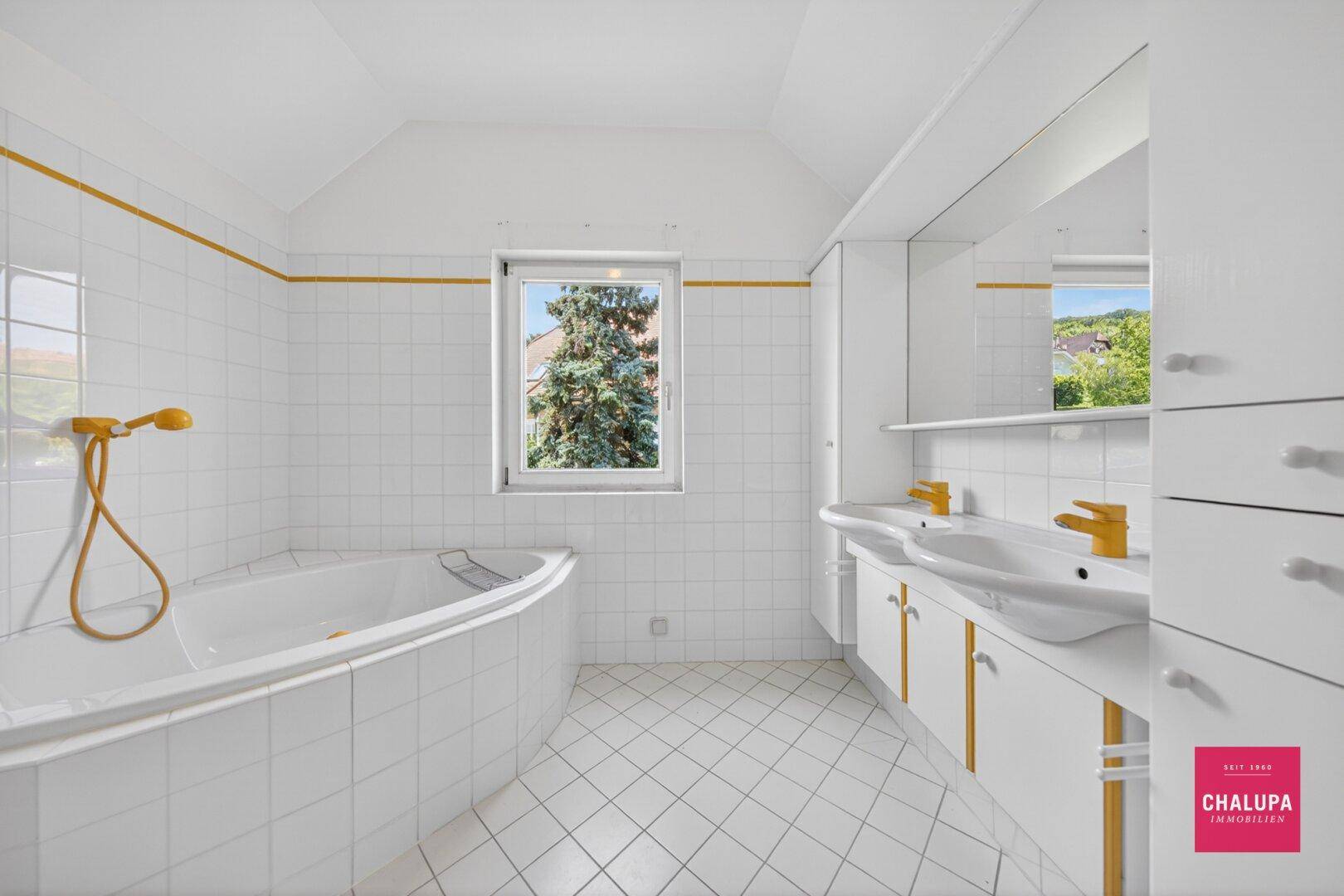 Geräumiges Badezimmer mit Doppelwaschbecken, Badewanne und Fenster.