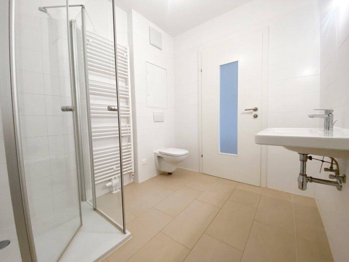 Modernes Badezimmer mit Duschkabine, wandhängendem WC und Handtuchheizkörper.