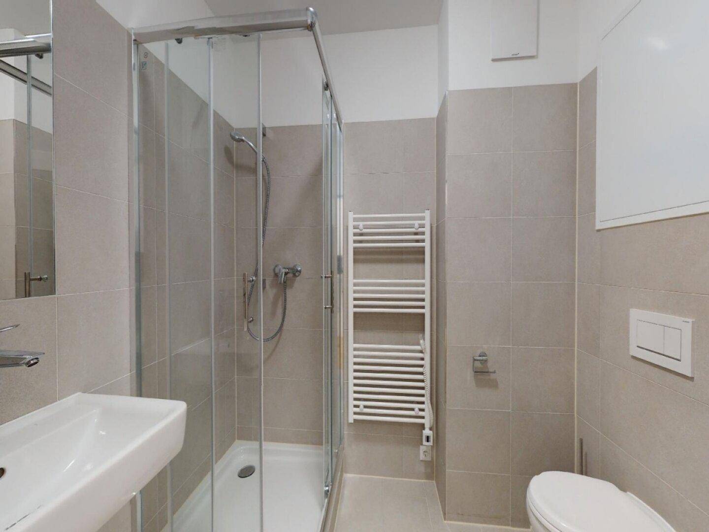 Modernes Badezimmer mit hellgrauen Fliesen, Duschkabine, Waschbecken und beheiztem Handtuchhalter.