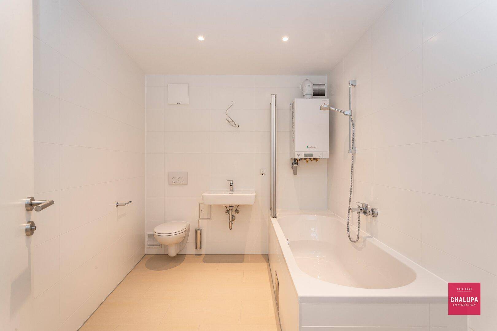 Modernes Badezimmer mit Badewanne, Toilette, Waschbecken und Wandheizung.