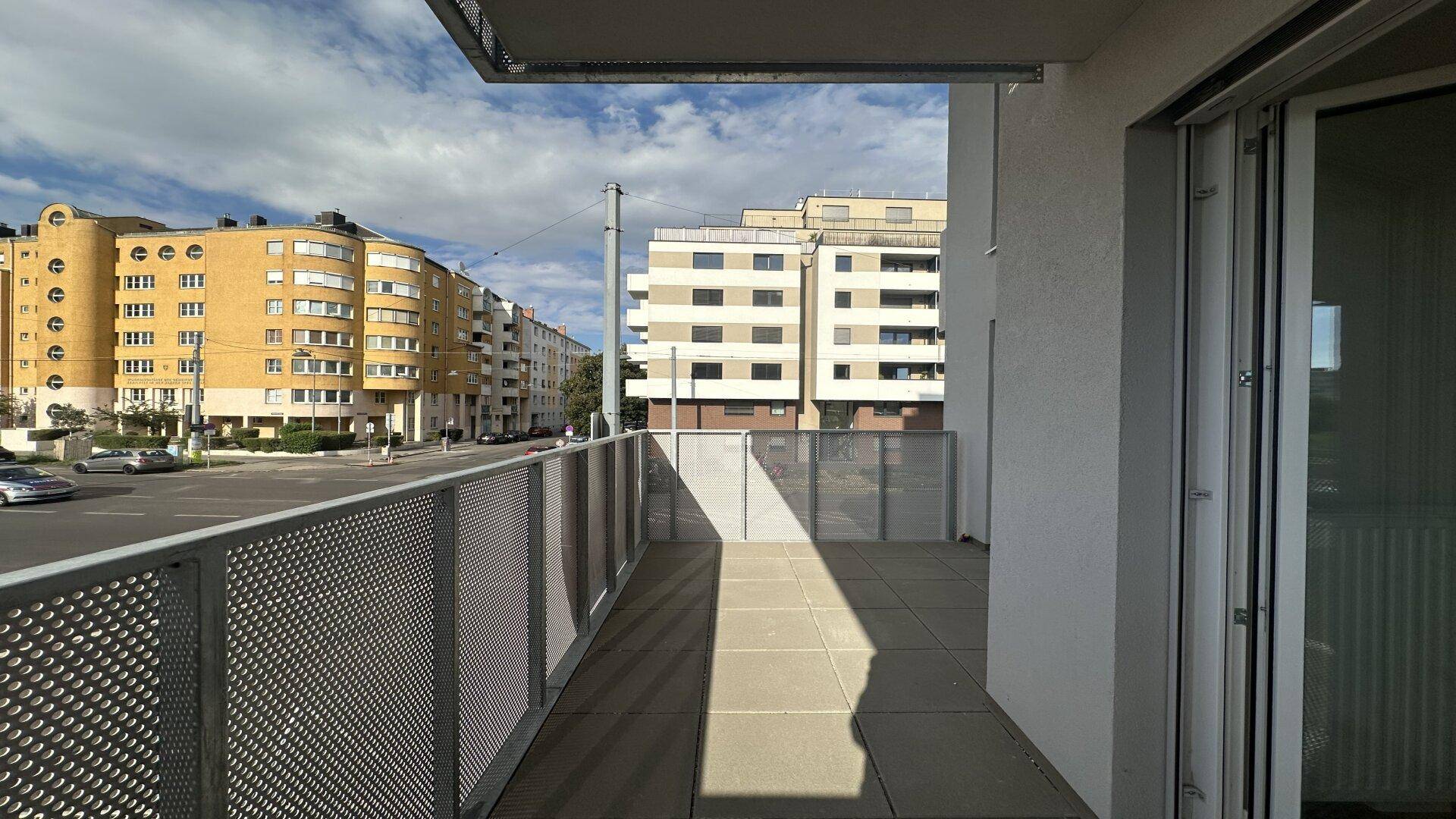 Geräumiger Balkon mit Fliesenboden und Blick auf die umliegenden Stadtgebäude.