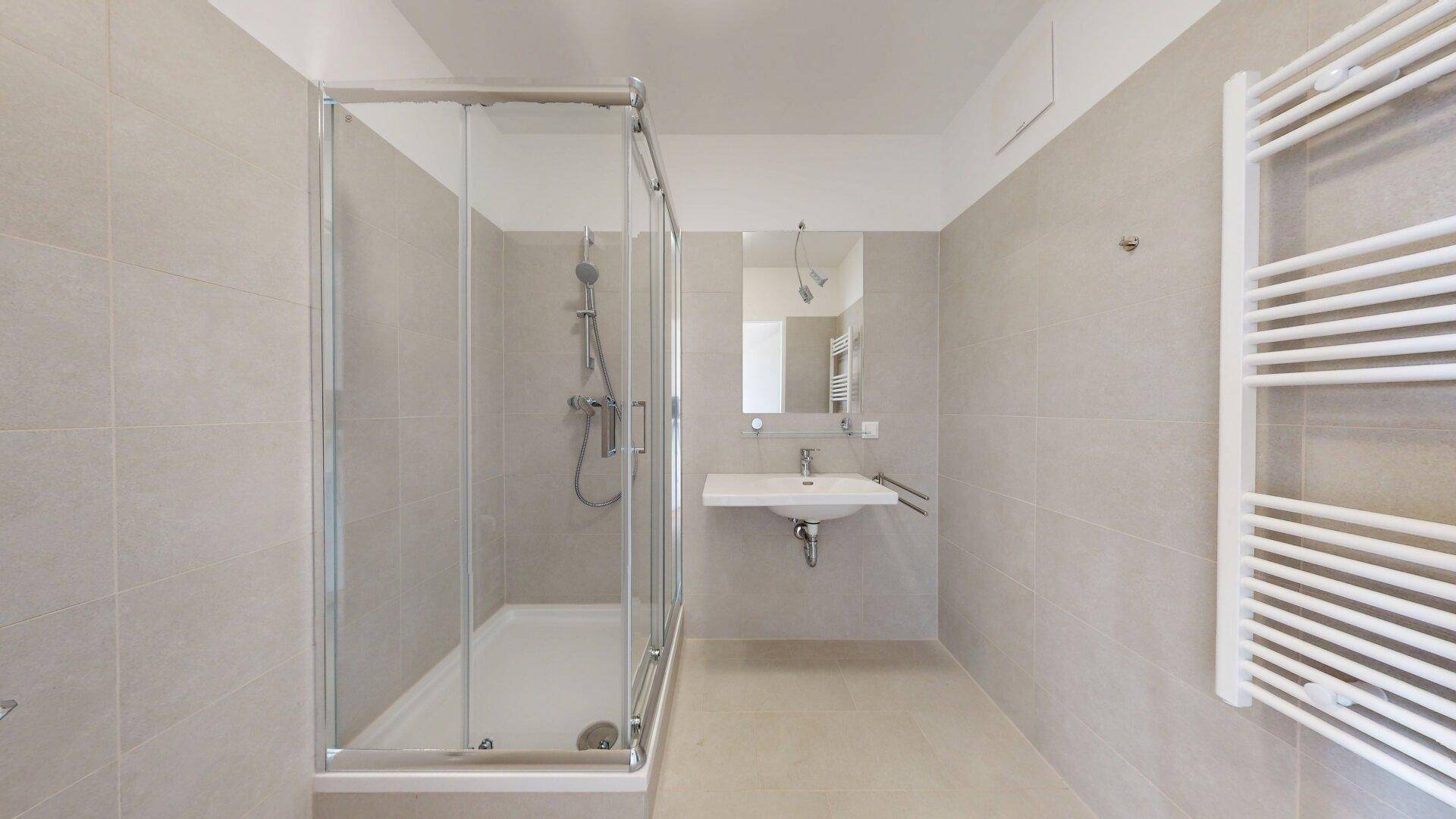 Modernes Badezimmer mit Duschkabine, Waschbecken und beheiztem Handtuchhalter.