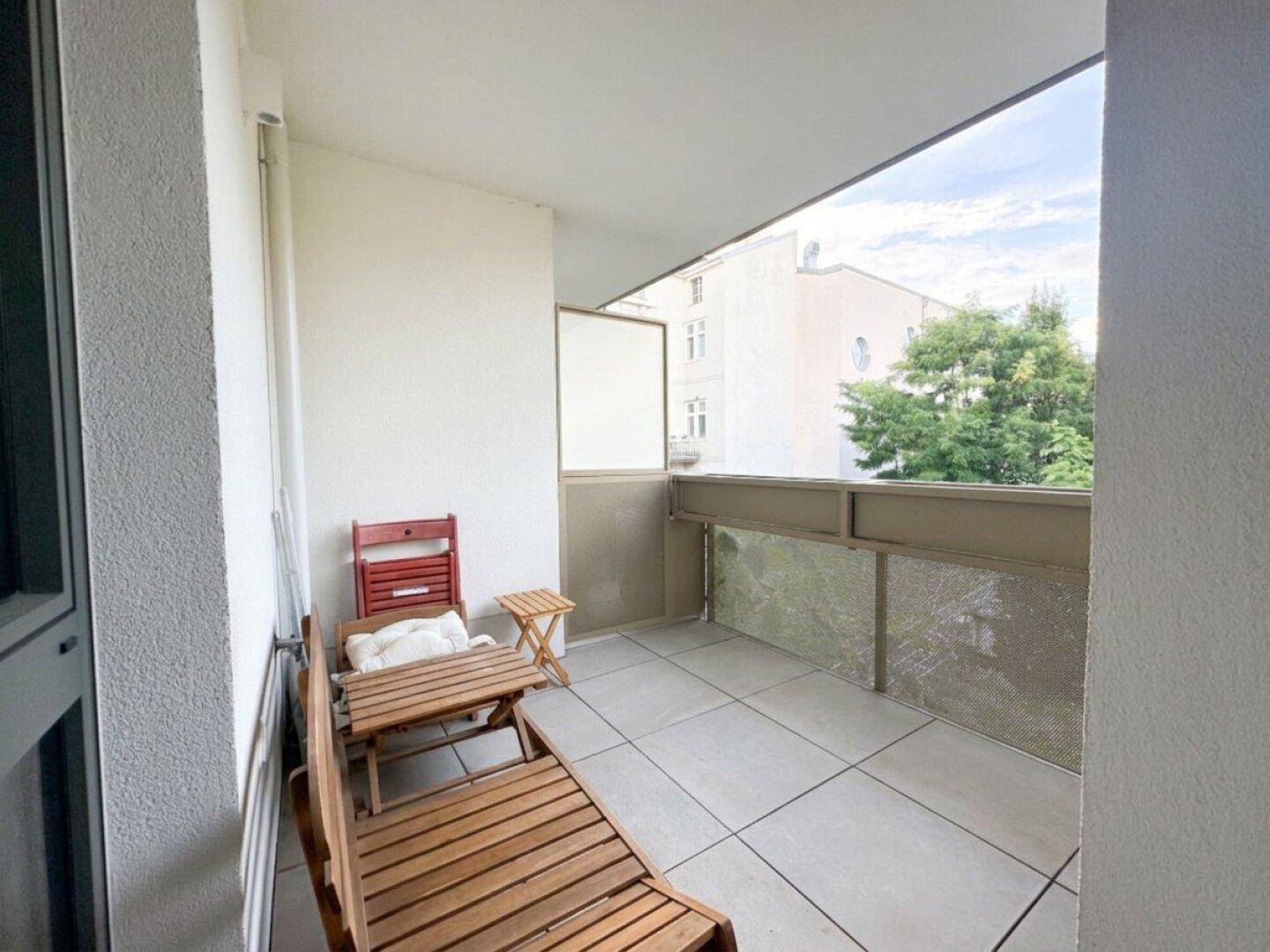 Gemütlicher Balkon mit Fliesenboden und Holzmöbeln, ideal zum Entspannen mit Blick auf die Umgebung.