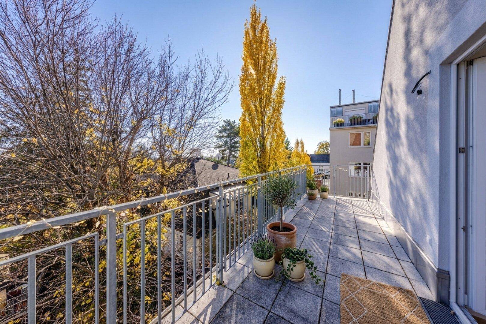Geräumiger Balkon mit Fliesenboden, Topfpflanzen und Blick auf die Umgebung.