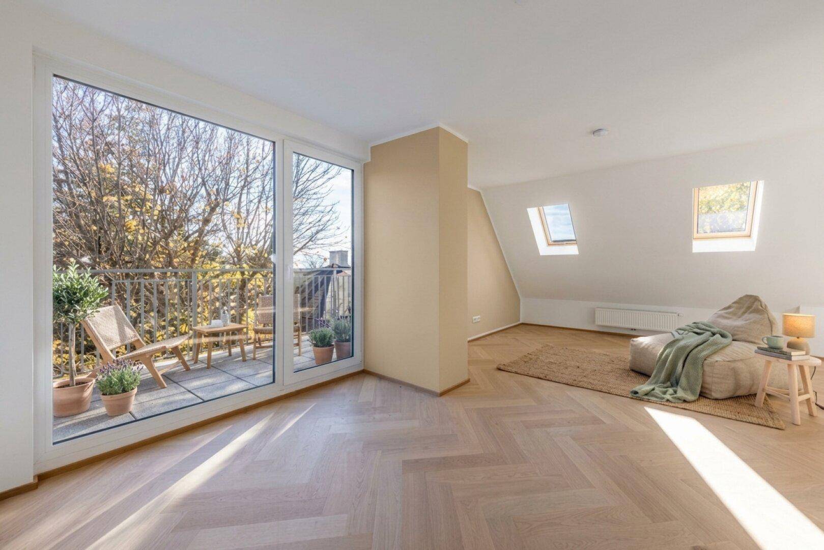 Heller Raum mit großem Fenster zum Balkon, zwei Dachfenstern und schrägen Decken.