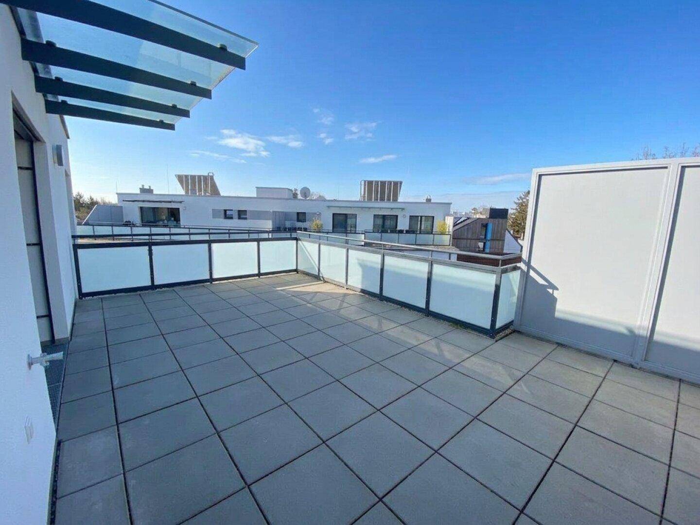 Weitläufige Dachterrasse mit Fliesenbelag und Blick auf die umliegenden Gebäude.