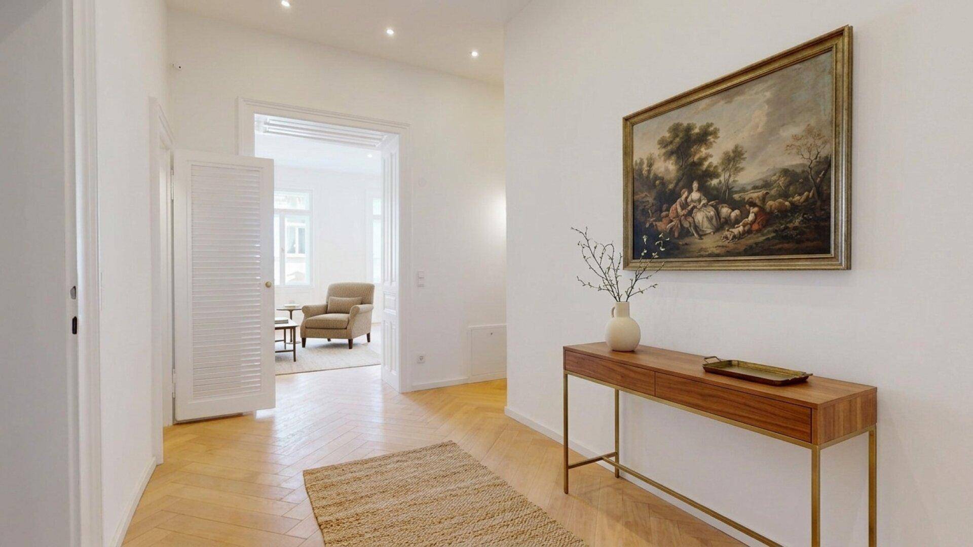Geräumiger Flur mit klassischem Gemälde, Fischgrätparkett und Blick in ein weiteres Zimmer.