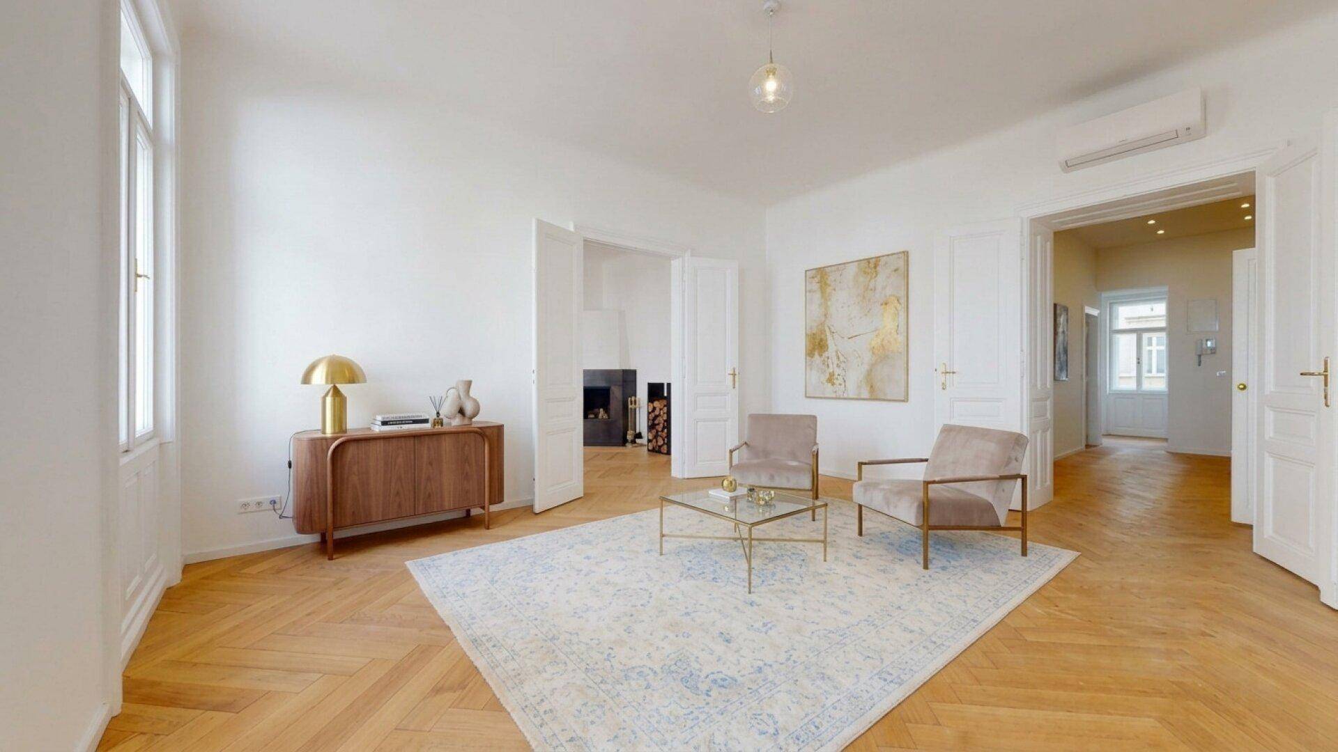 Helles Wohnzimmer mit stilvollen Sesseln, Couchtisch und Fischgrätparkettboden.