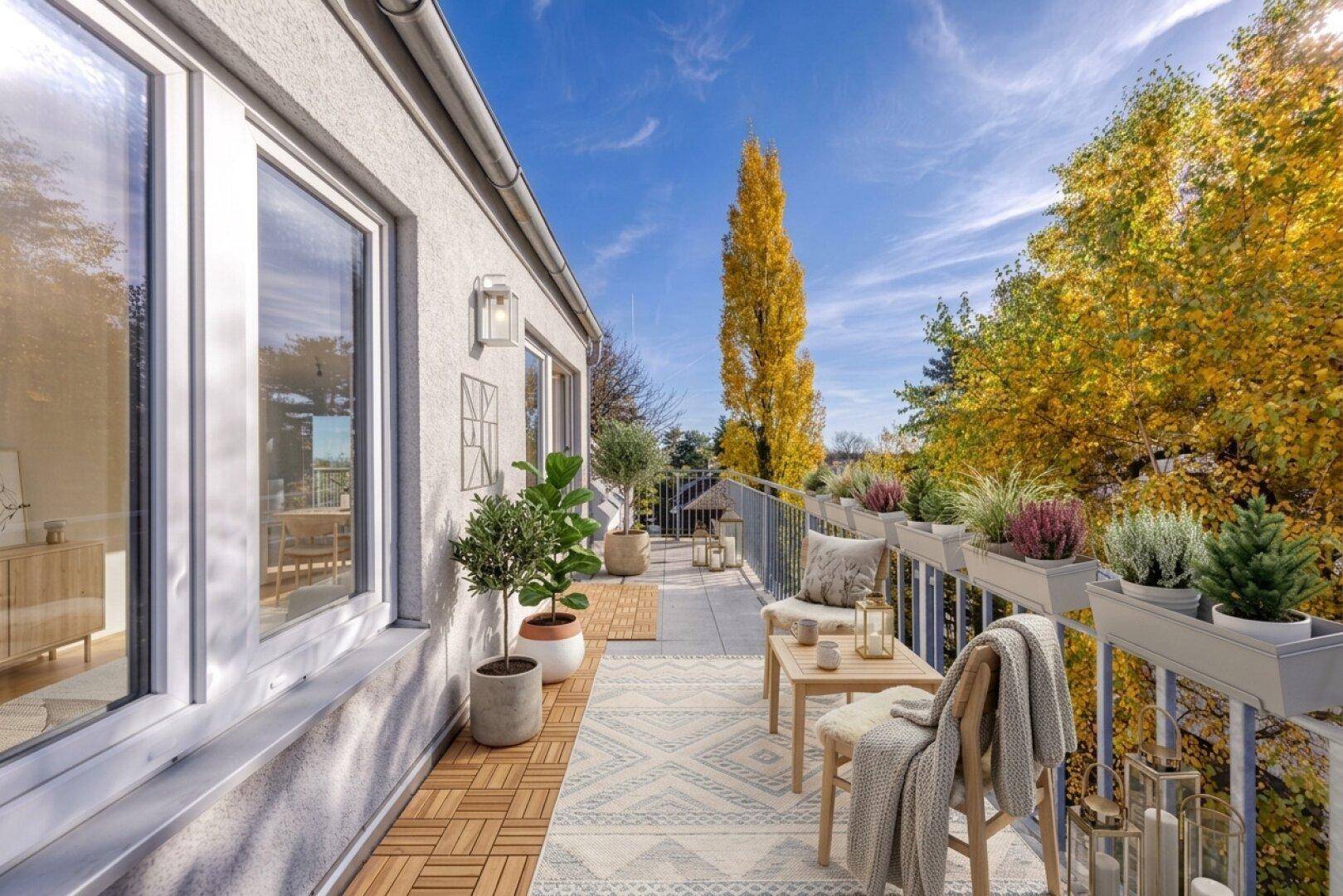 Langer, schmaler Balkon mit Holzbodenfliesen, Sitzgelegenheiten und Blick auf herbstliche Bäume.
