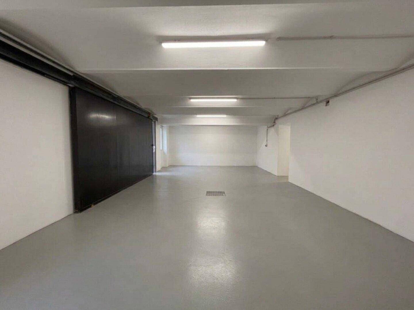 Geräumiger, leerer Raum mit glattem Boden und Leuchtstoffröhren, ideal als Garage oder Lagerfläche.