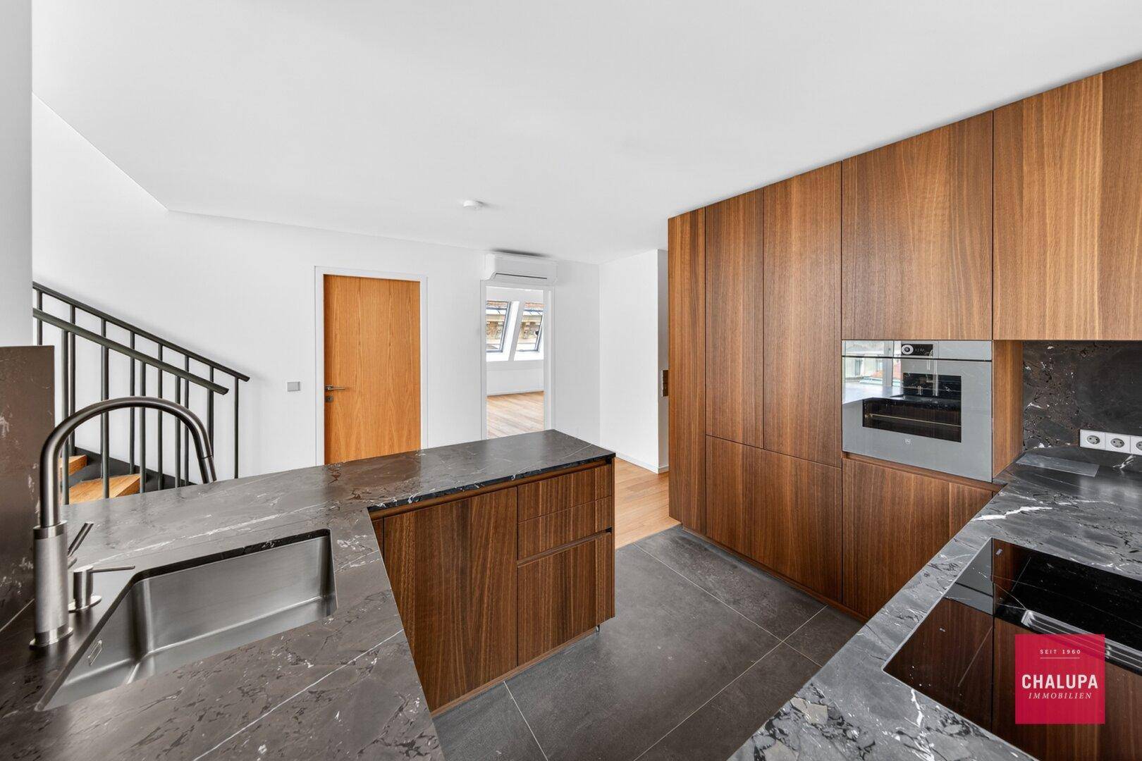 Elegante Holzküche mit dunklen Marmorarbeitsplatten, integriertem Backofen und modernem Design.