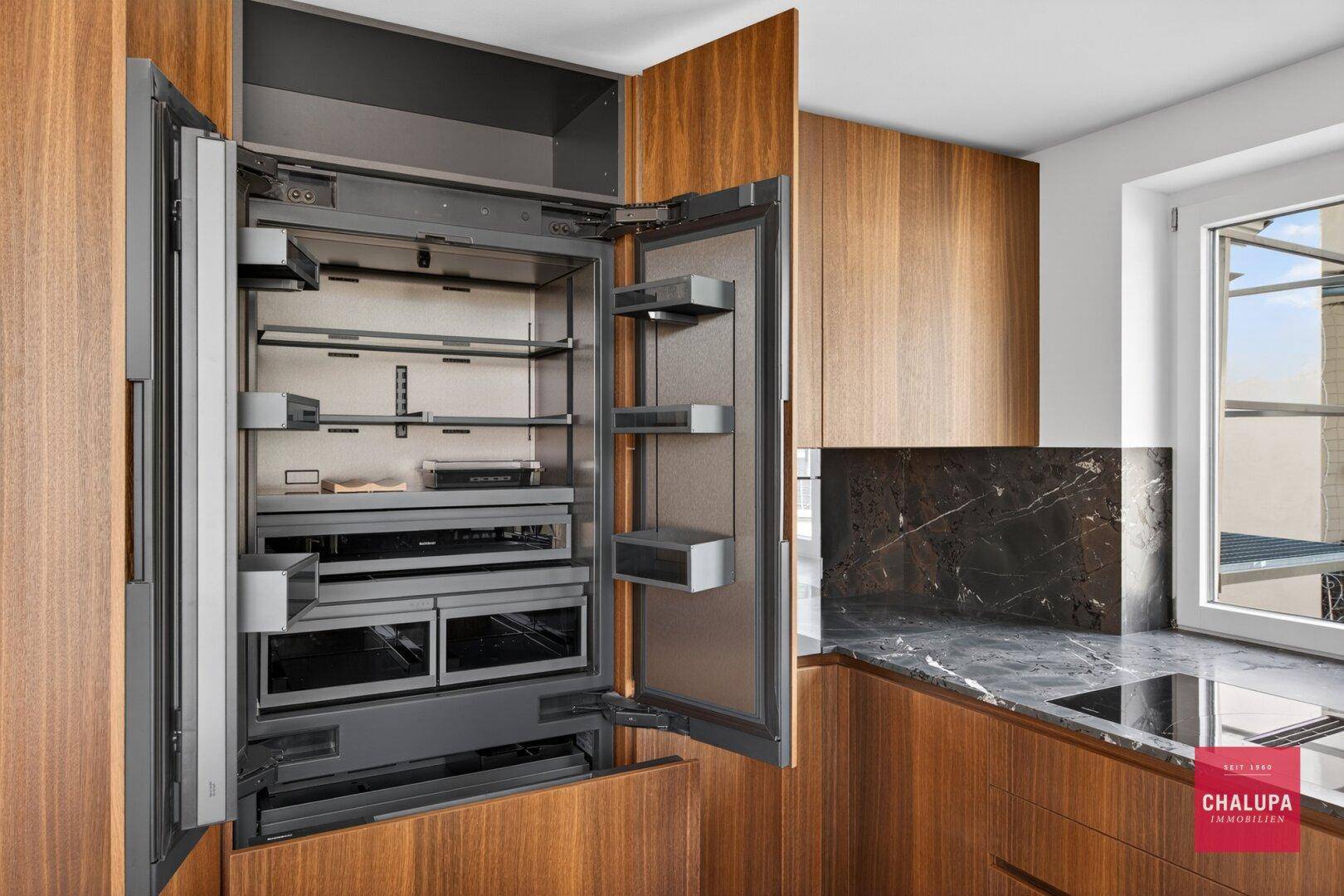 Hochwertiger, integrierter Kühlschrank in einer modernen Holzküche mit viel Stauraum.