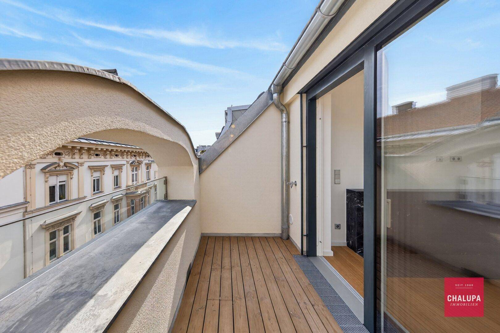 Kleiner Balkon mit Holzboden und Blick auf die historische Architektur der Umgebung.
