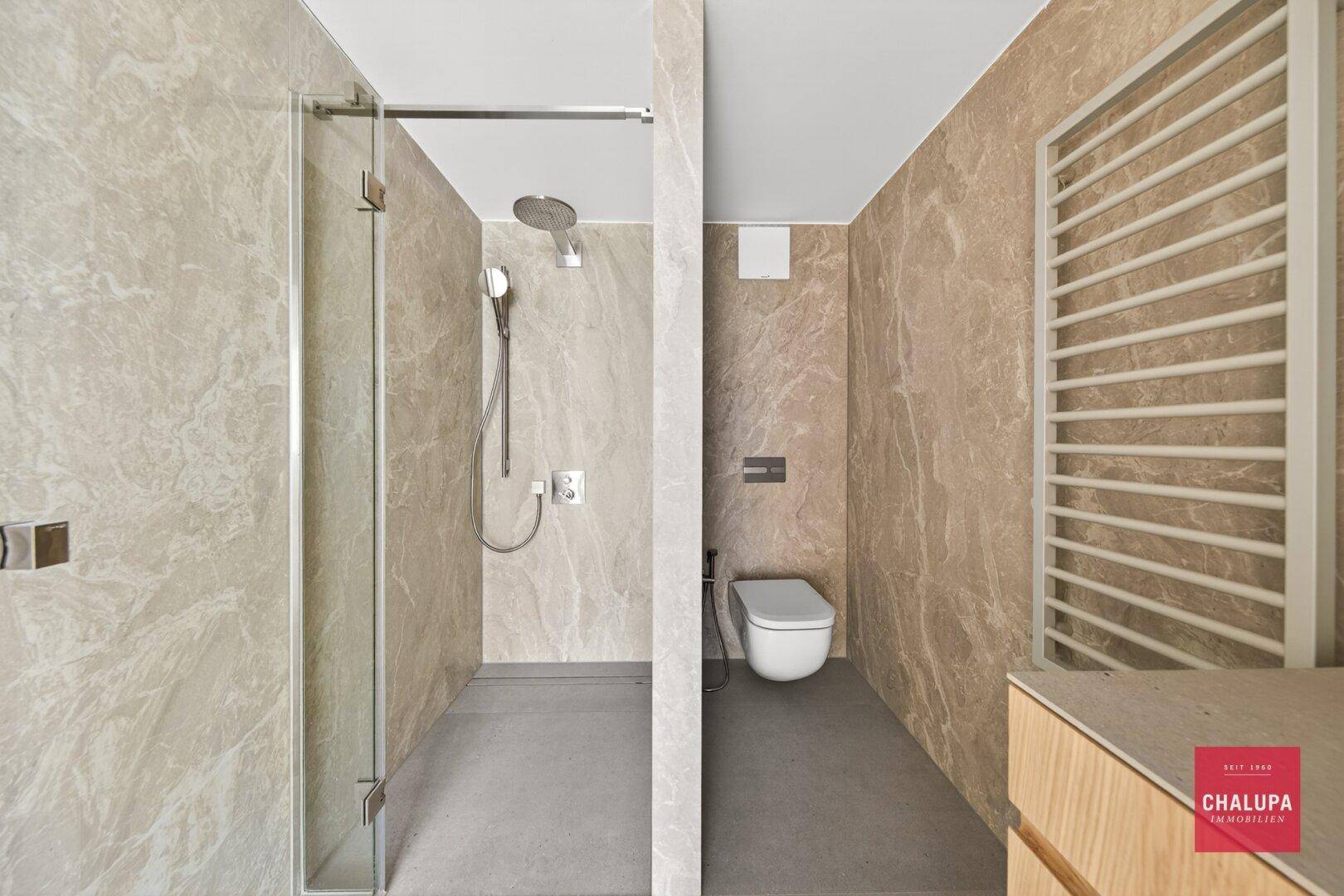 Modernes Badezimmer mit begehbarer Dusche, wandhängendem WC und beheiztem Handtuchhalter.