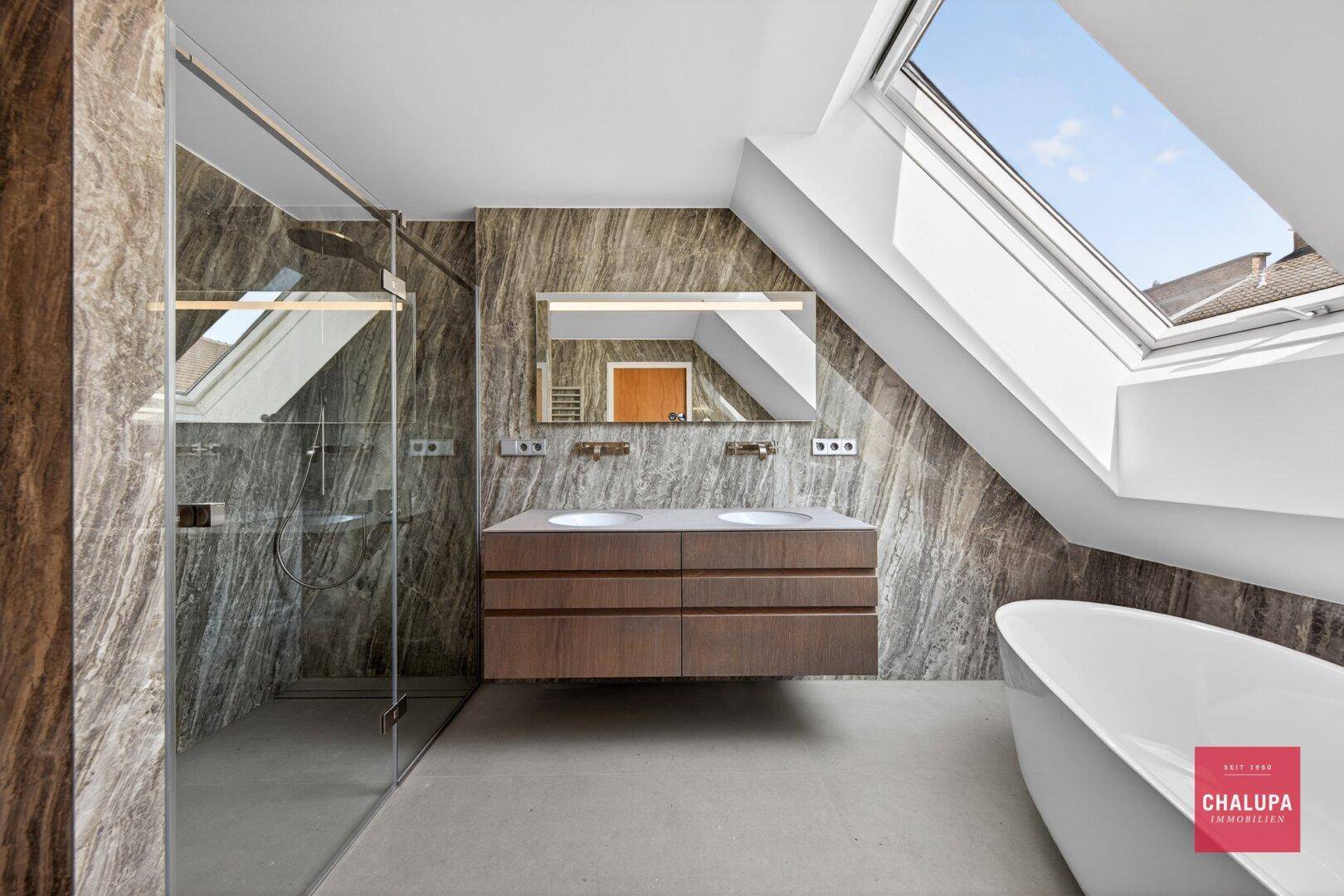 Luxuriöses Badezimmer mit begehbarer Dusche, Doppelwaschbecken, freistehender Badewanne und Dachfenster.