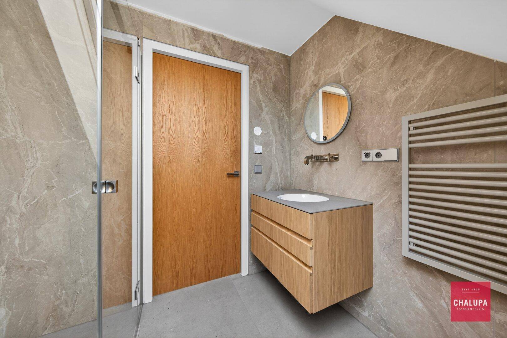 Modernes Badezimmer mit begehbarer Dusche, Einzelwaschbecken und beheiztem Handtuchhalter.