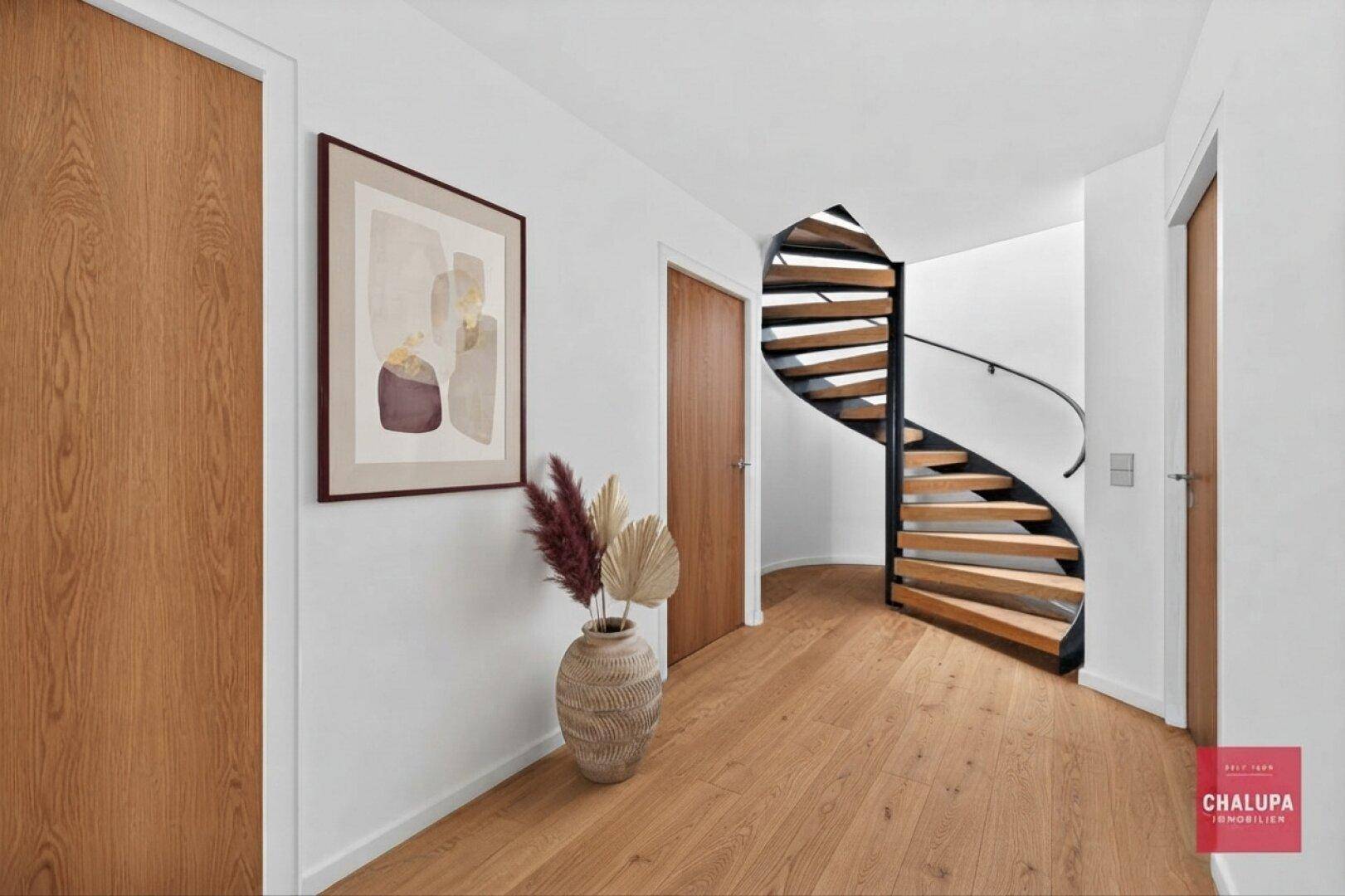 Heller Flur mit eleganter Holztreppe und modernen Holzböden.