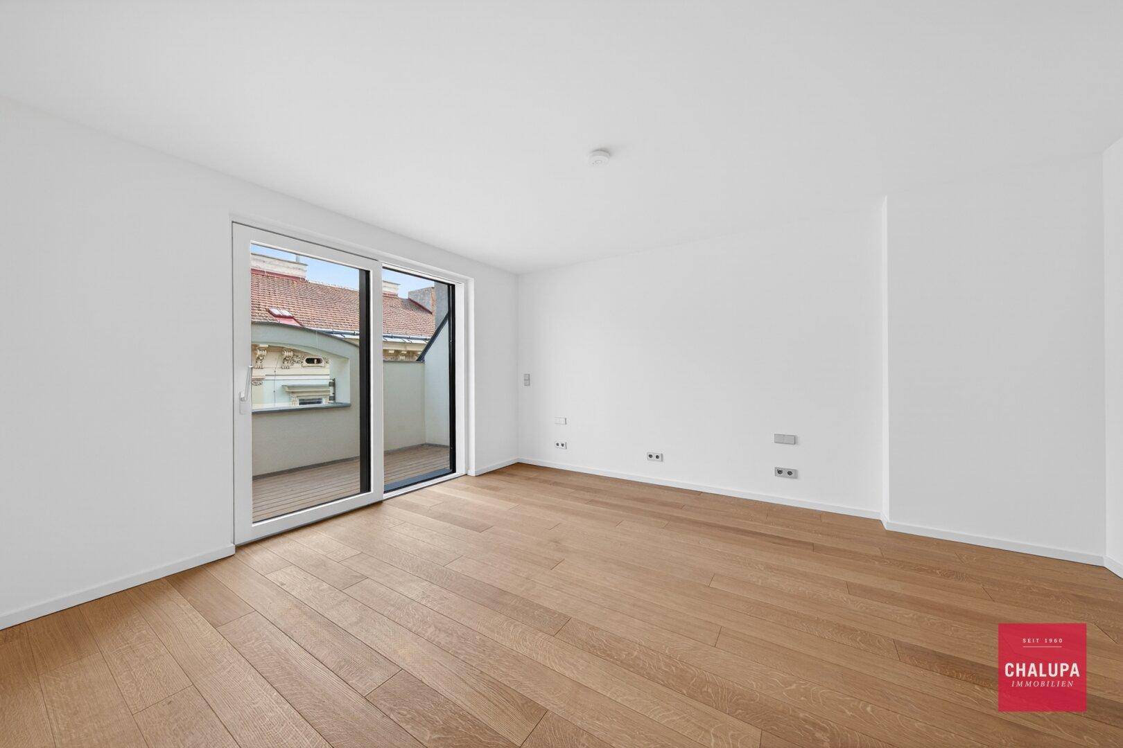 Heller Raum mit Holzboden und großer Schiebetür zum Balkon, ideal für Wohn- oder Schlafzimmer.