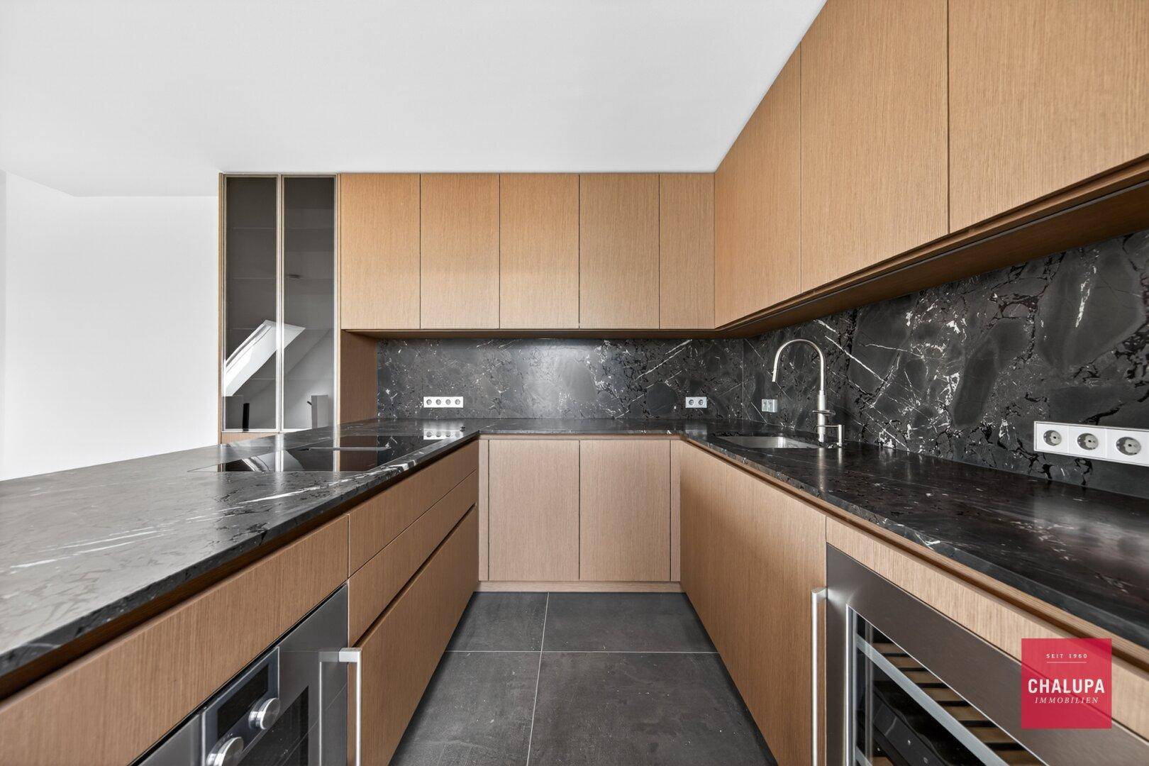 Elegante Küche mit Holzschränken, schwarzer Marmorarbeitsplatte und integrierten Geräten.