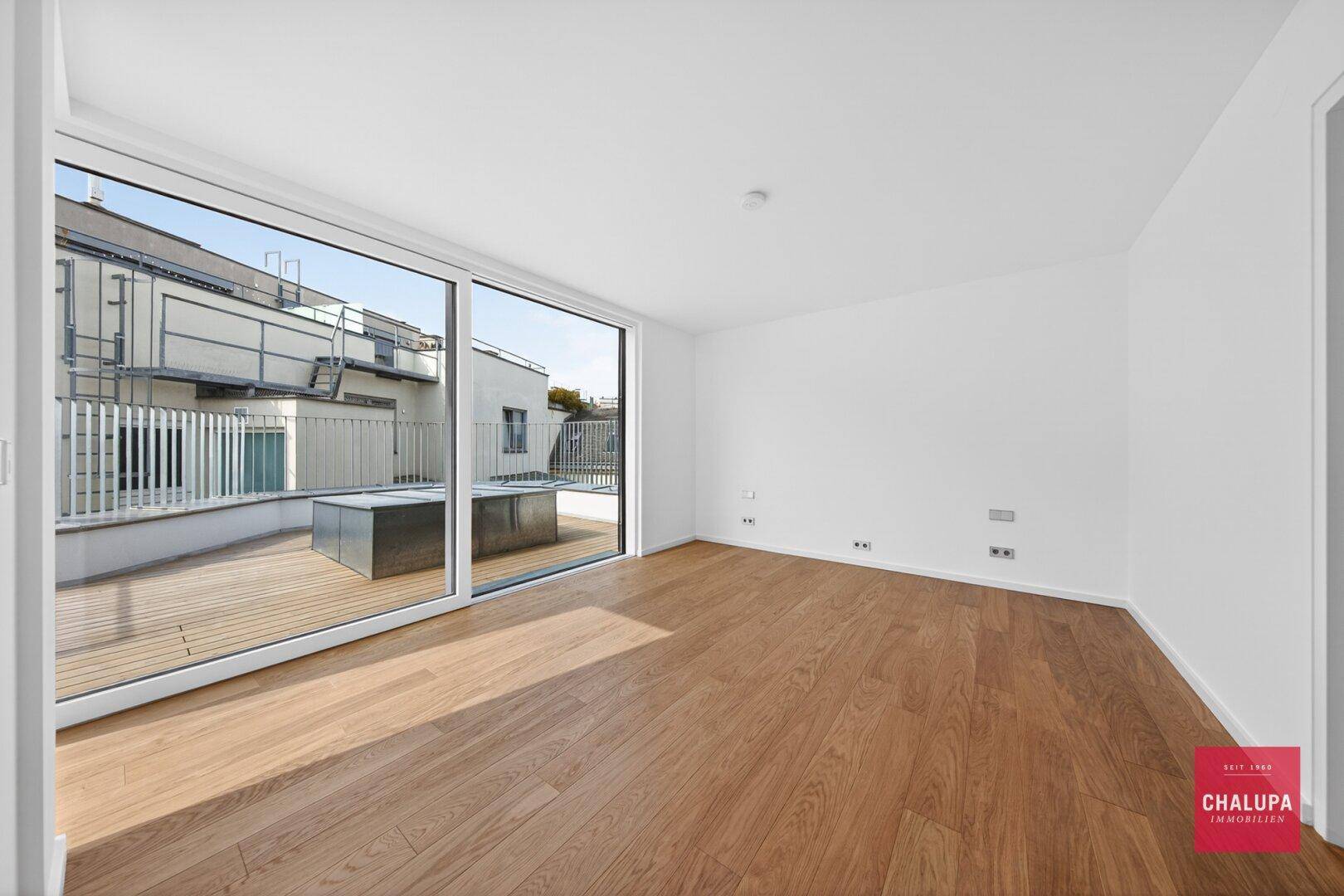 Geräumiger, heller Raum mit Holzboden und großem Terrassenzugang mit Feuerstelle.