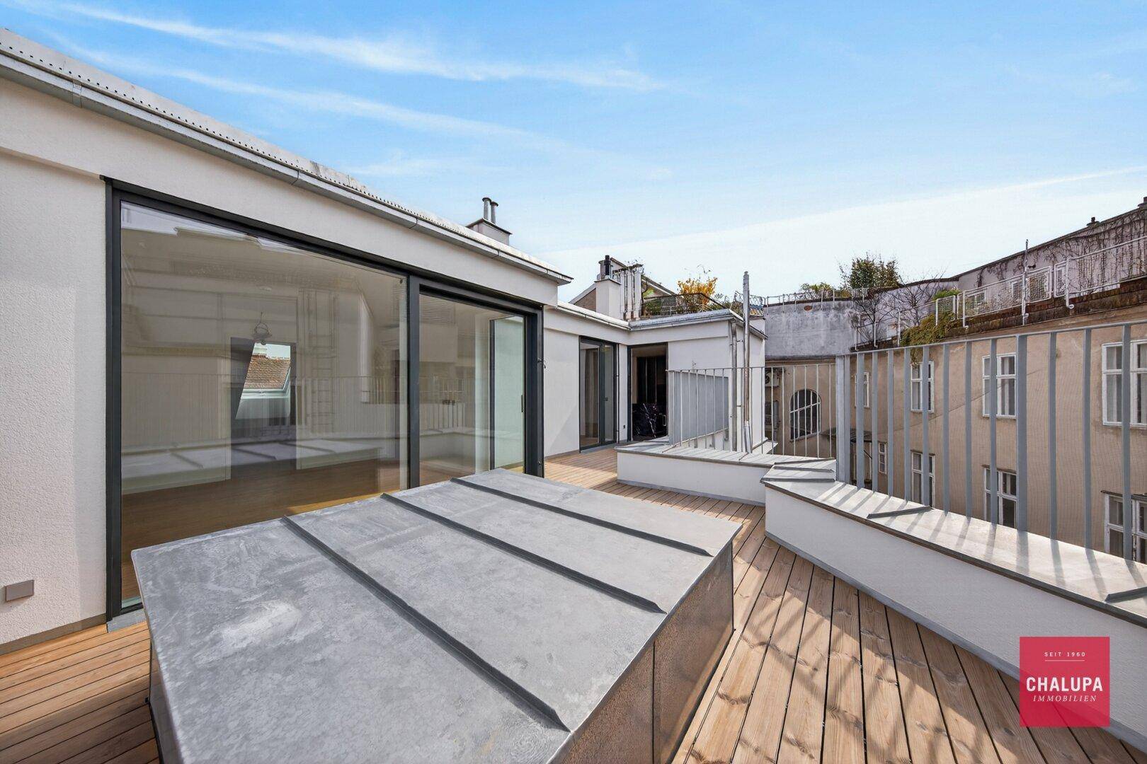 Große Dachterrasse mit Holzdeck und Blick auf die historische Architektur der Umgebung.
