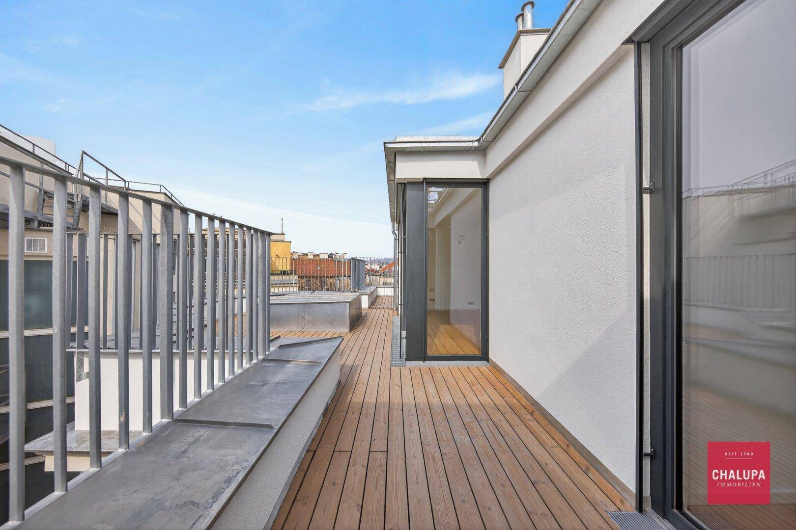 Weitläufige Dachterrasse mit Holzdeck und Panoramablick über die Stadt.