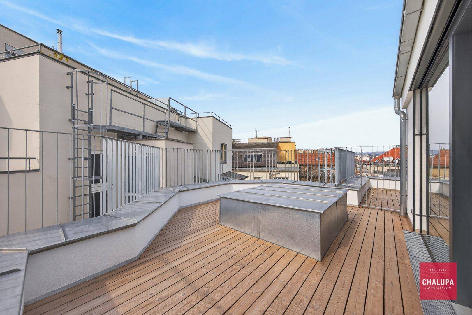 Weitläufige Dachterrasse mit Holzdeck und weitem Blick über die Stadtlandschaft.