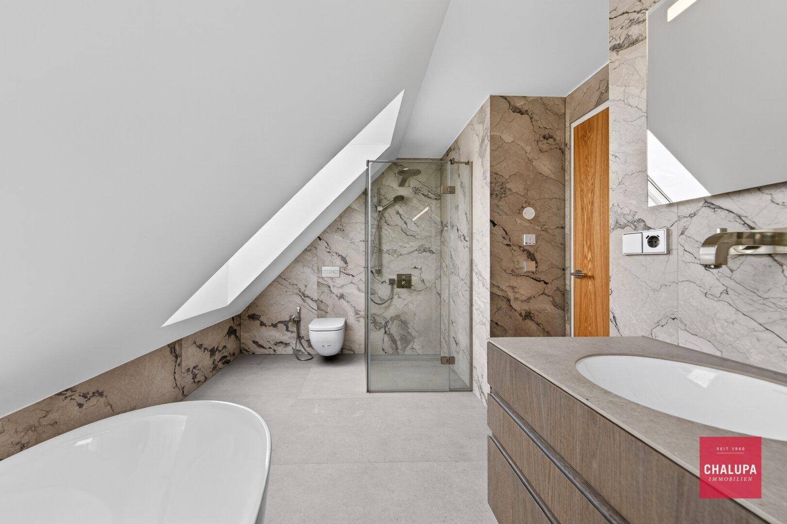 Elegantes Badezimmer mit begehbarer Dusche, Wand-WC und Doppelwaschbecken unter der Dachschräge.