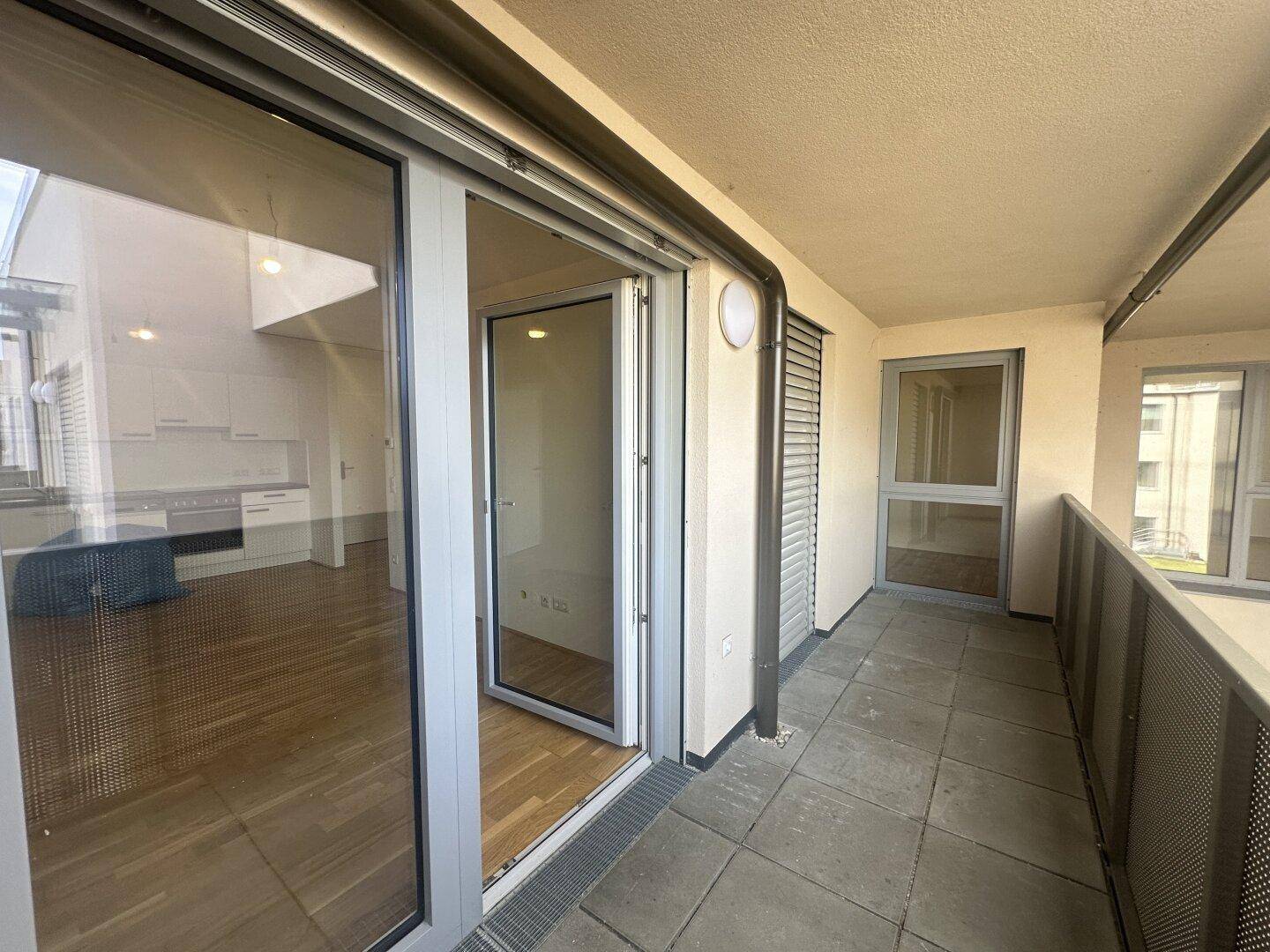 Balkon mit Fliesenboden und Zugang zu den Innenräumen, mit Blick auf die Umgebung.