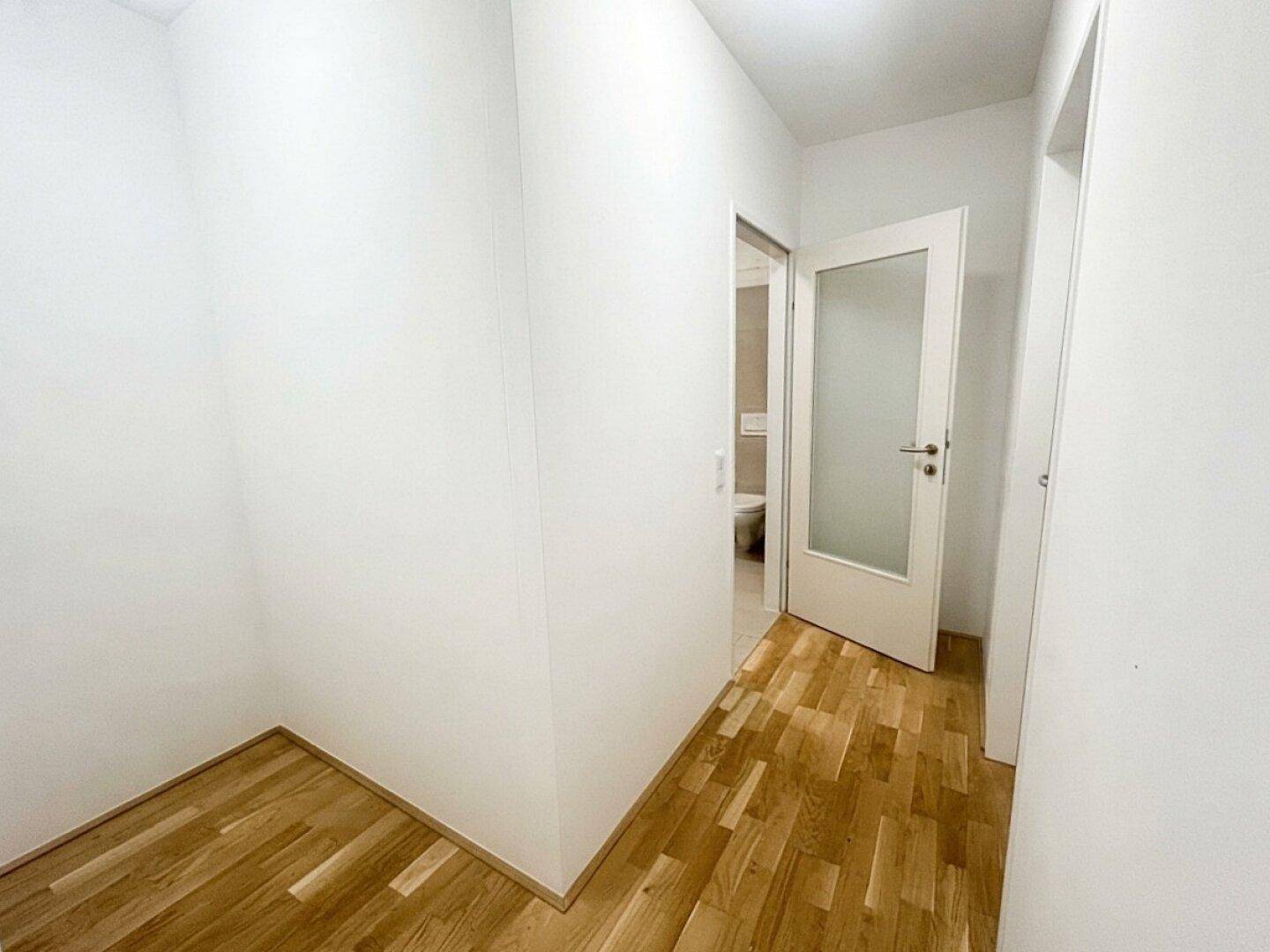 Kleiner Flurbereich mit Parkettboden und Zugang zu einem Badezimmer oder WC.