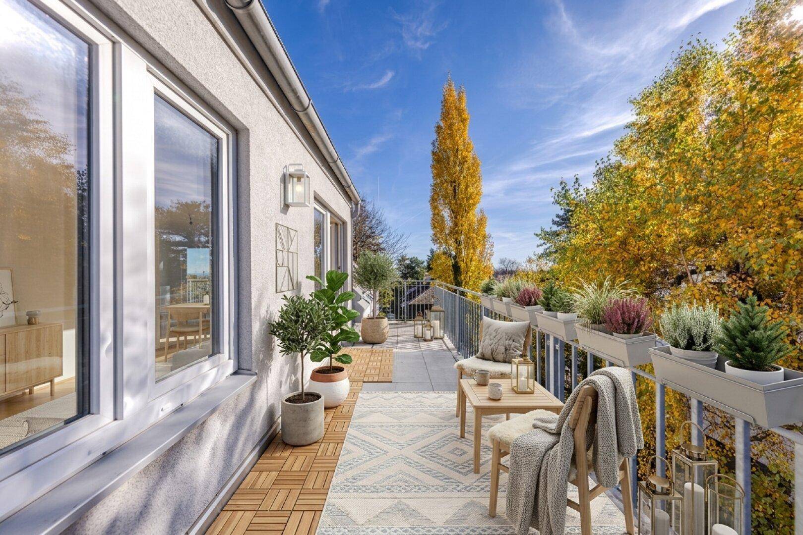Möblierter Balkon mit Holzbodenfliesen, Teppich und Topfpflanzen, umgeben von Herbstbäumen.