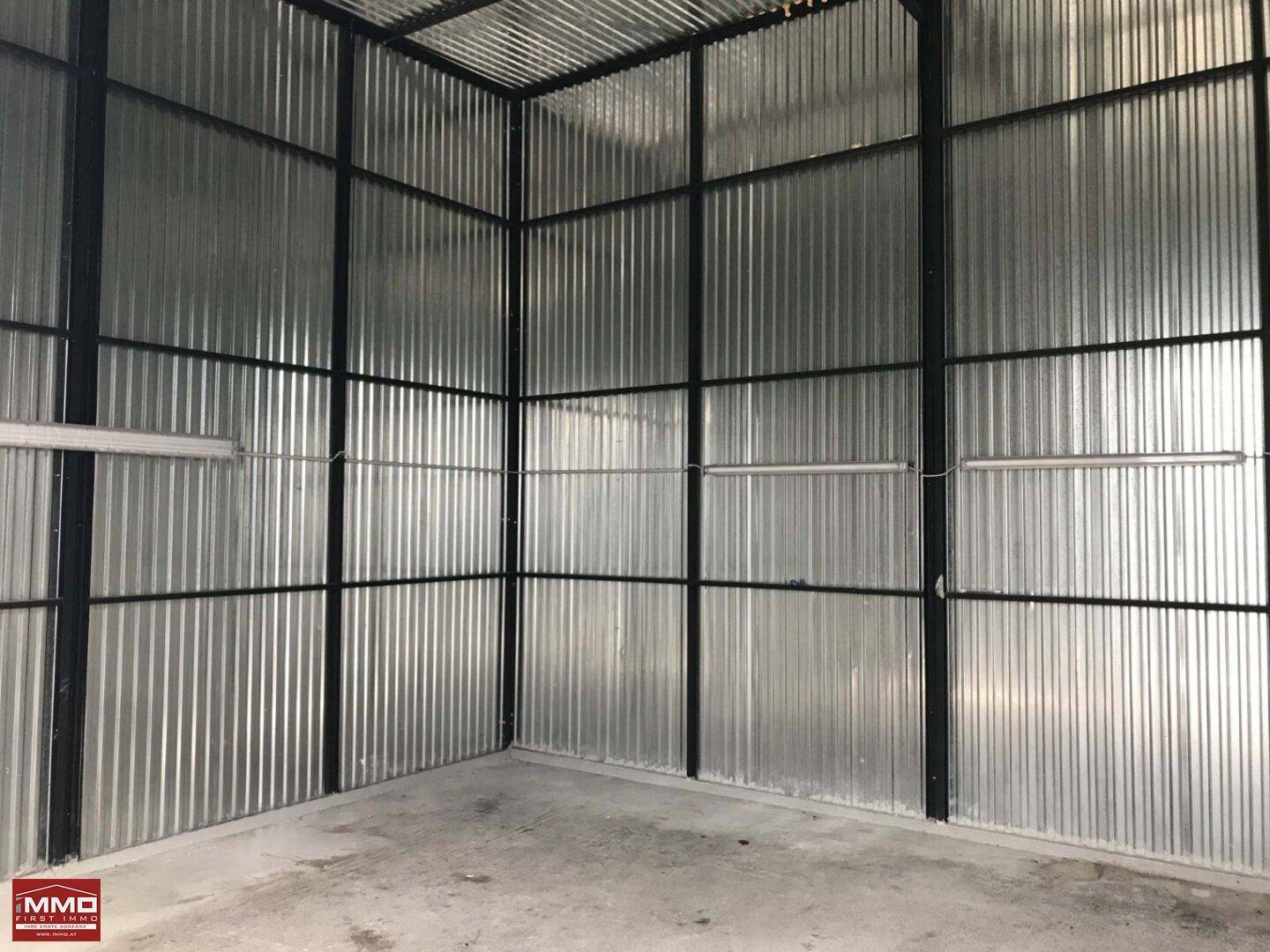 Leerer Industrieraum mit Wellblechwänden, Betonboden und sichtbarer Metallkonstruktion, ideal für Lagerung.