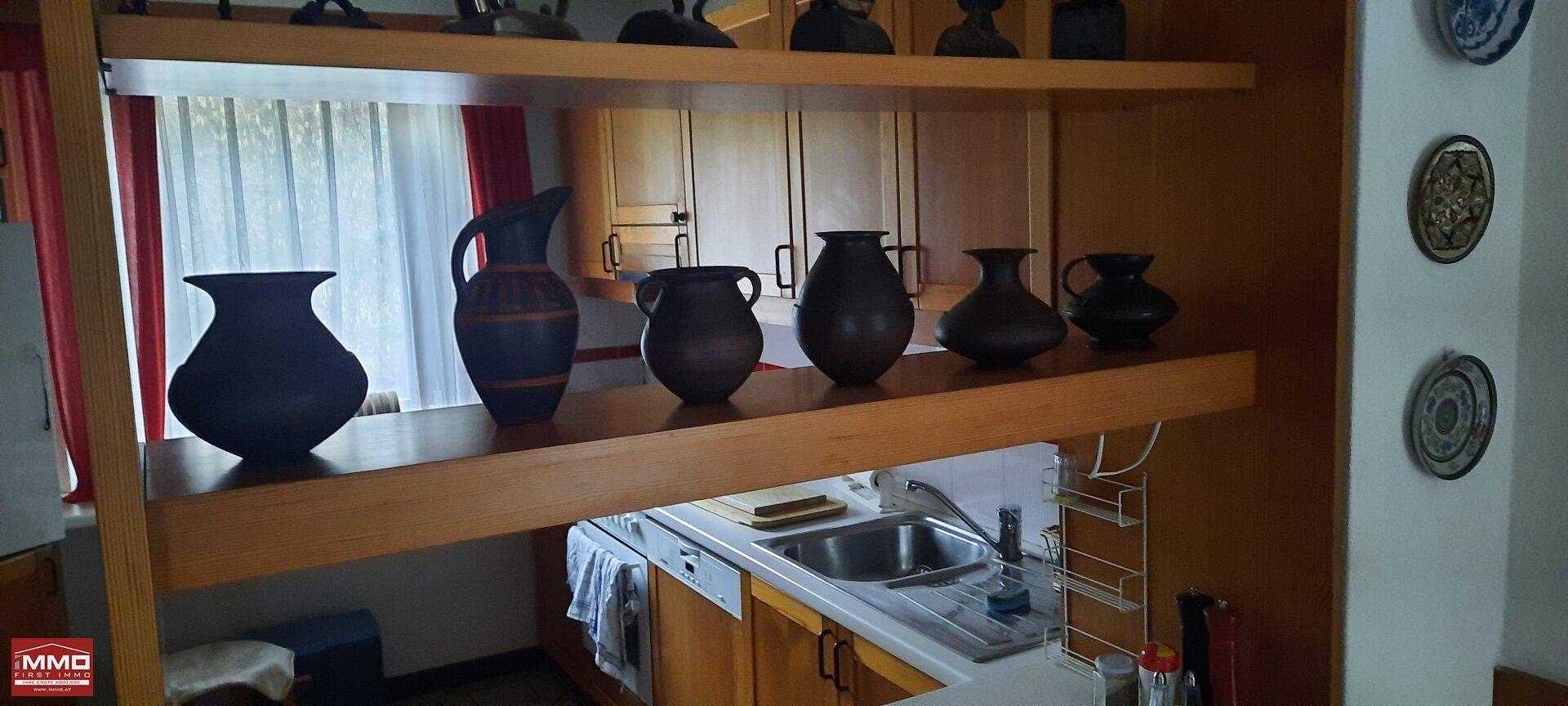 Detailansicht der Küche mit Spülbecken und dekorativen Keramikgefäßen auf einem Regal.