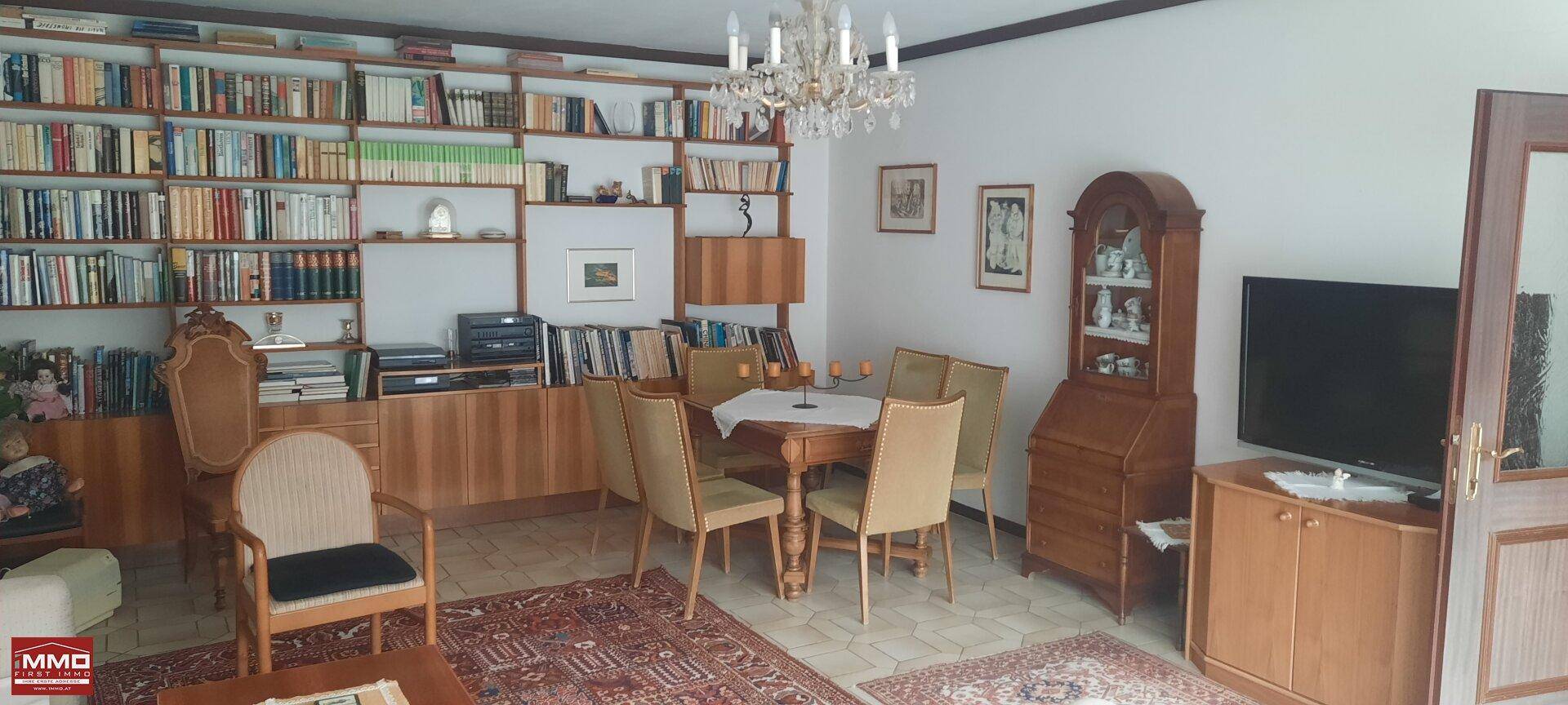 Klassischer Wohn- und Essbereich mit umfangreicher Bücherwand, Kronleuchter und traditionellen Möbeln.