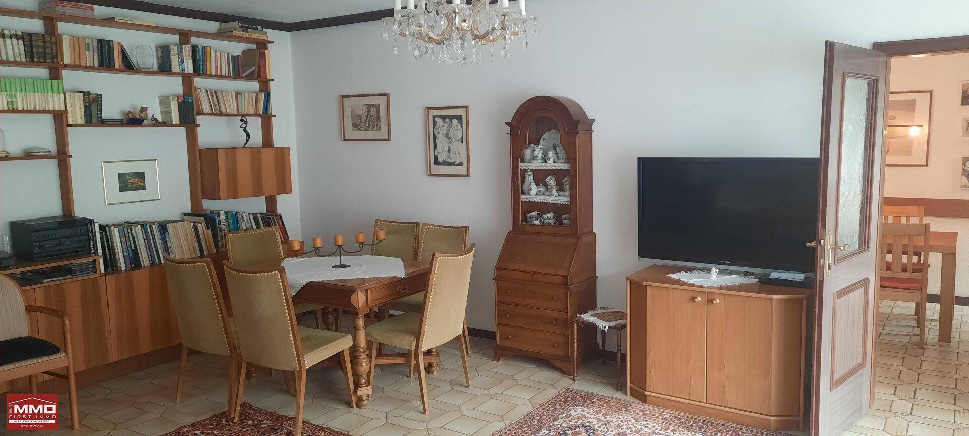 Geräumiger Wohn-Essbereich mit Esstisch, Fernseher und einer großen Bücherwand.